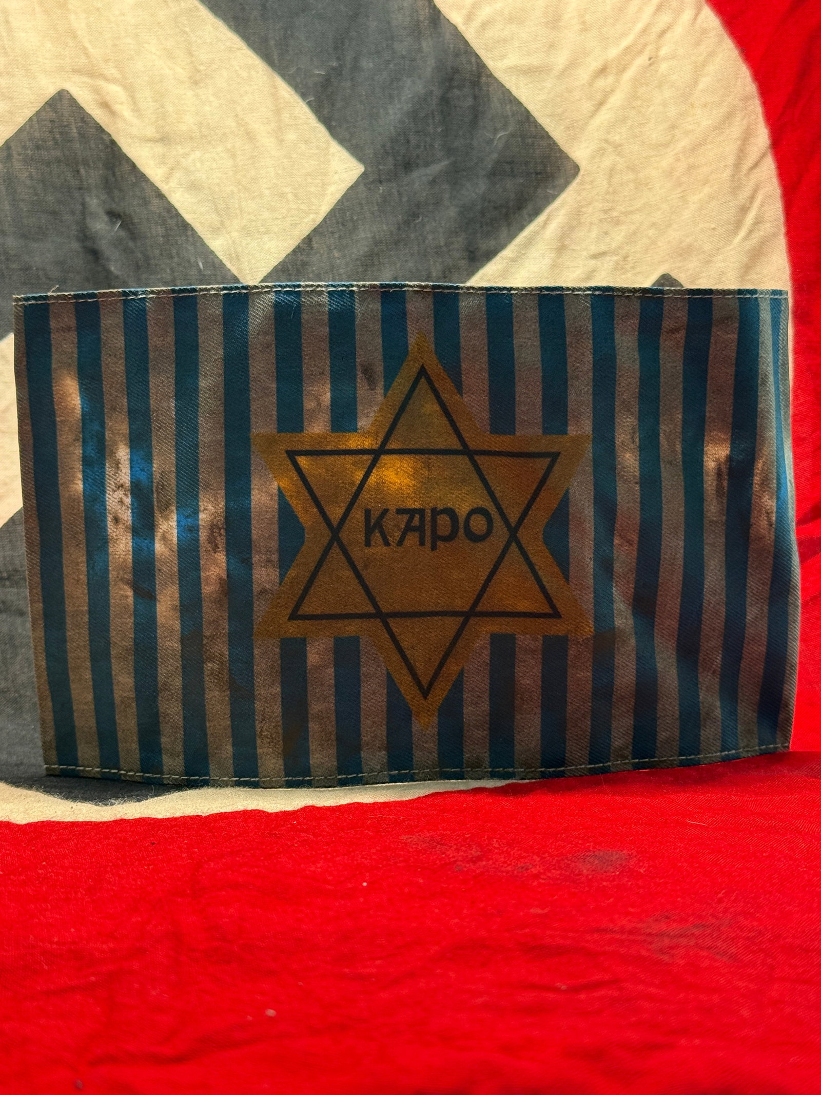 WWII Jewish KAPO Star Of David Concentration Camp Prisoner Identification Armband: This cloth armband displays alternating blue and white stripes with a yellow Star of David bearing the word "Kapo." During the Holocaust, kapos were prisoners appointed by SS authorities to supervise 