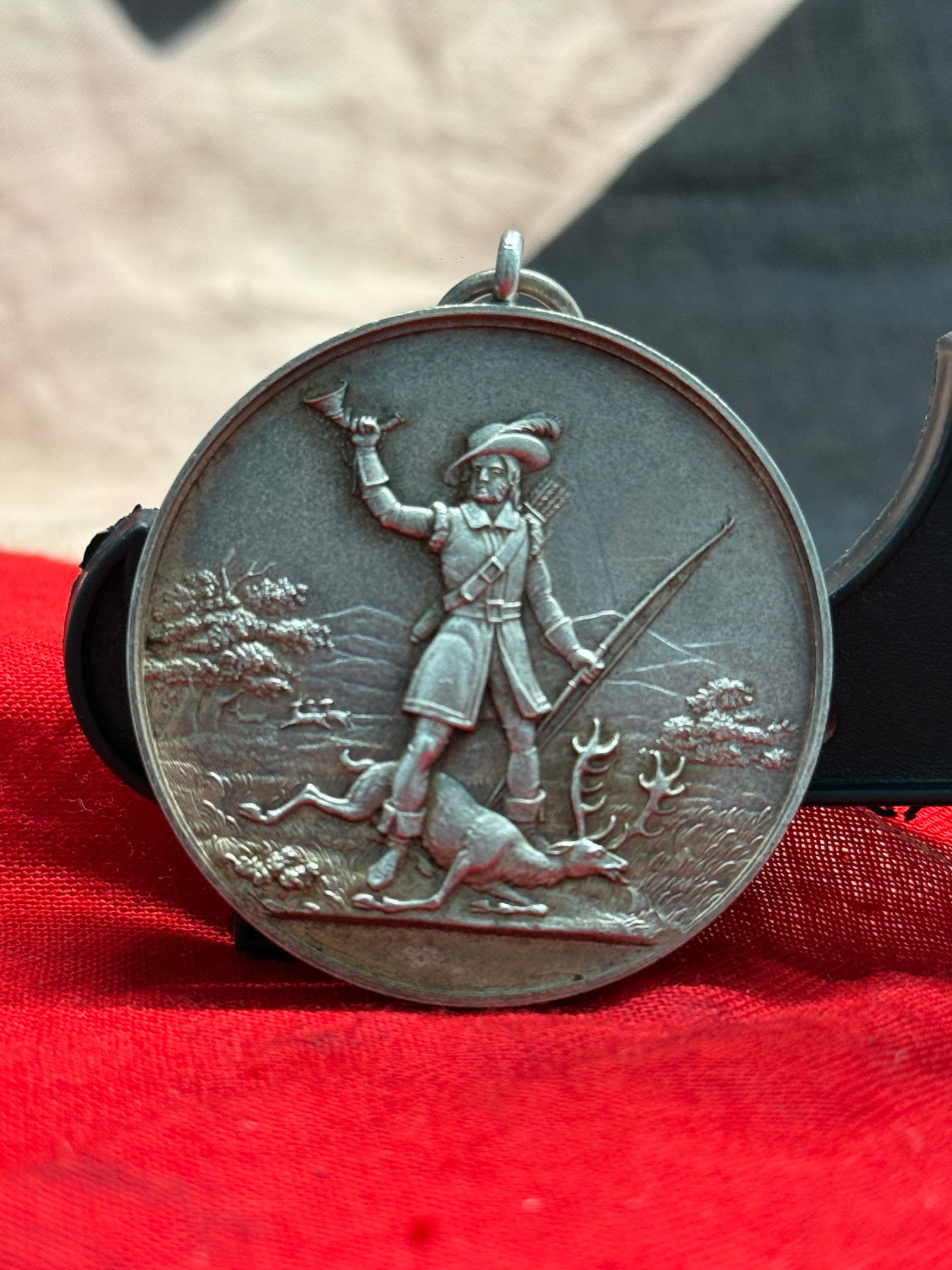 WW2 German Hunting Association Prize Medal: This medal depicts a traditional huntsman standing triumphantly over harvested game while sounding a hunting horn, with a rifle in his opposite hand against a countryside landscape. The reverse is sur