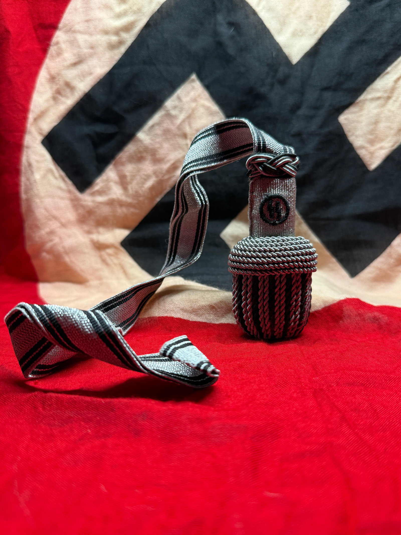 WWII German Waffen-SS Officer's Sword Portepee Knot (Silver): This WWII German Waffen-SS Officer's Sword Portepee Knot features the distinctive silver-and-black woven strap with a finely braided silver acorn and embroidered SS runic emblem on the stem. Officer p