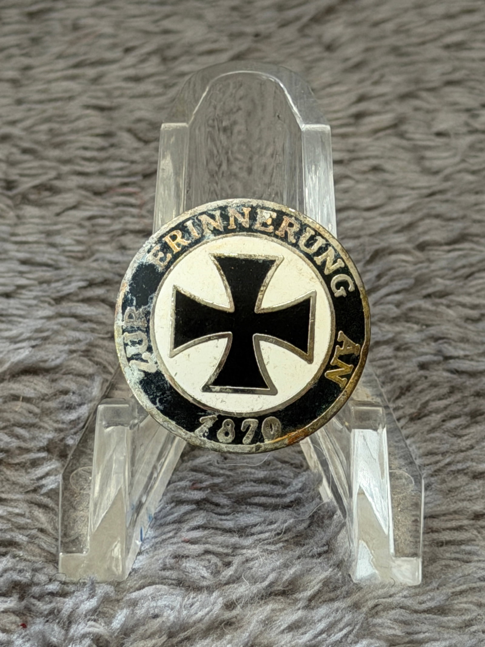WWII German Iron Cross "Wir Erinnern 1870" Commemorative Enamel Badge: This WWII German Iron Cross "Wir Erinnern 1870" Commemorative Enamel Badge features a black Iron Cross centered within a white field and surrounded by a black enamel border bearing the inscription "WI