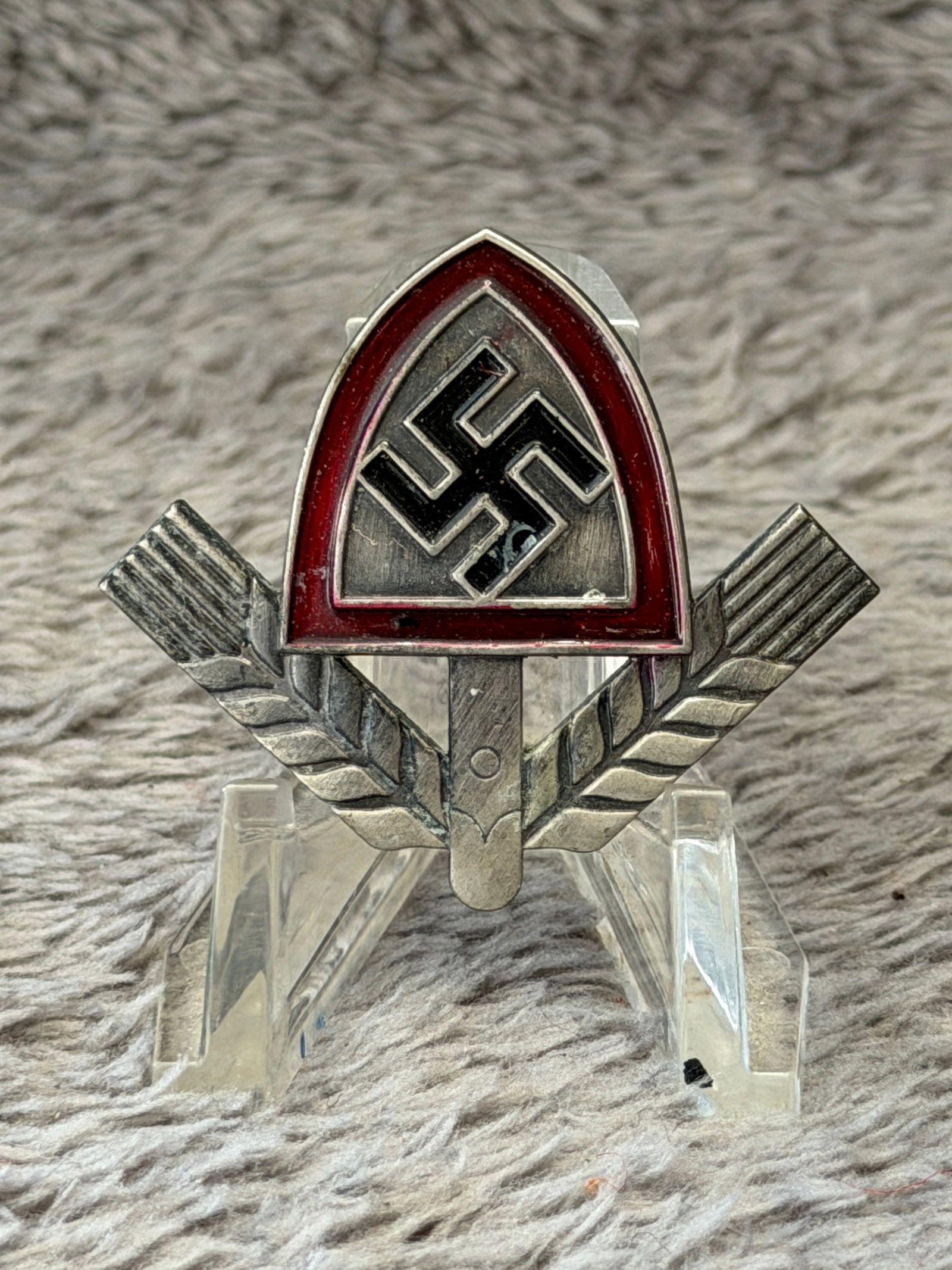 WWII German Reichsarbeitsdienst (RAD) Leader's Sports Badge: This WWII German Reichsarbeitsdienst (RAD) Leader's Sports Badge features the distinctive RAD spade-shaped emblem with a black swastika set against a silver field, bordered in translucent red enamel, 