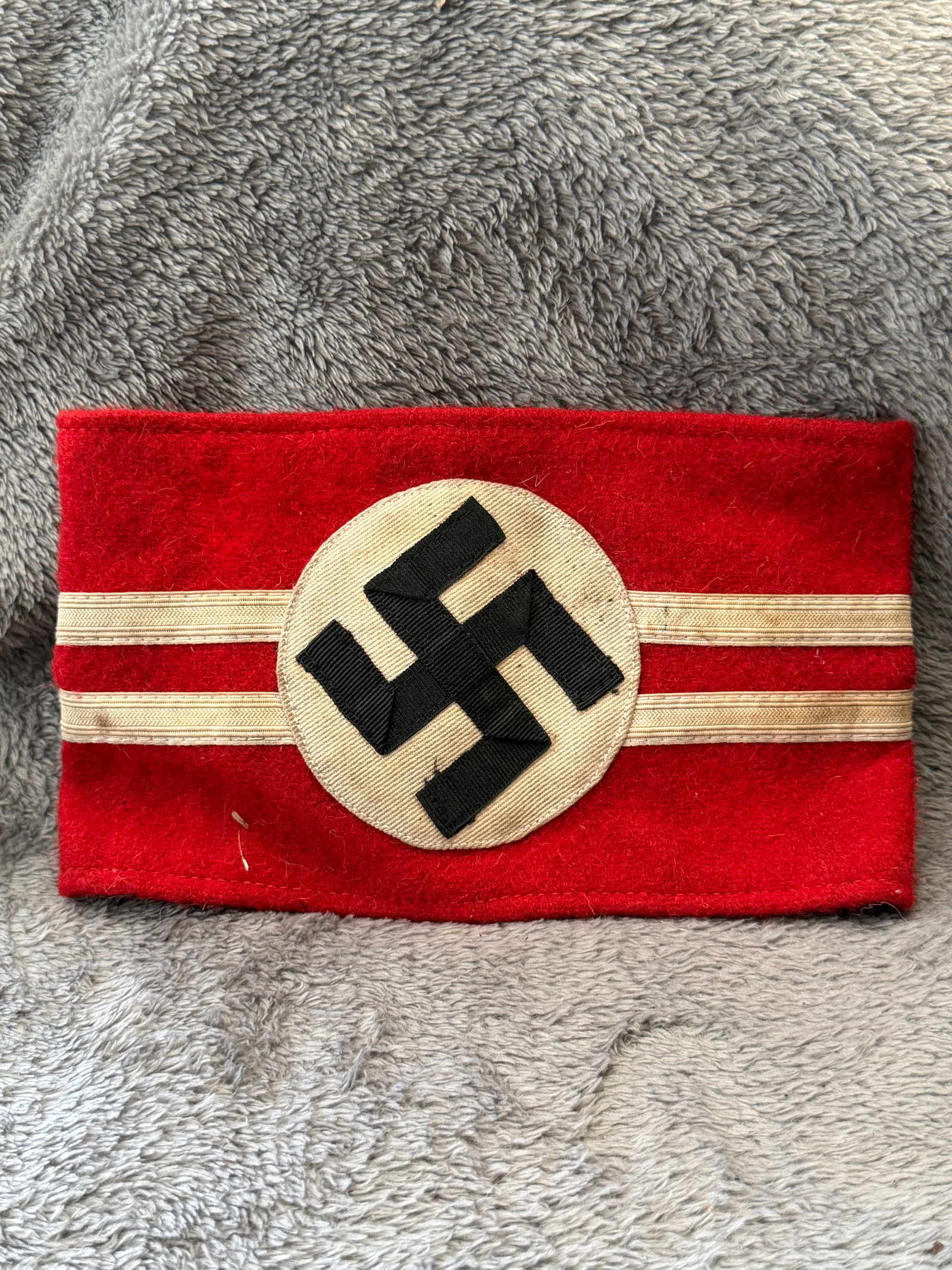 WWII German NSDAP Political Leader Red Armband with RZM Tag: This WWII German NSDAP Political Leader Red Armband is constructed of red wool with a separately applied white roundel featuring a black swastika and is finished with dual horizontal silver-colored ra
