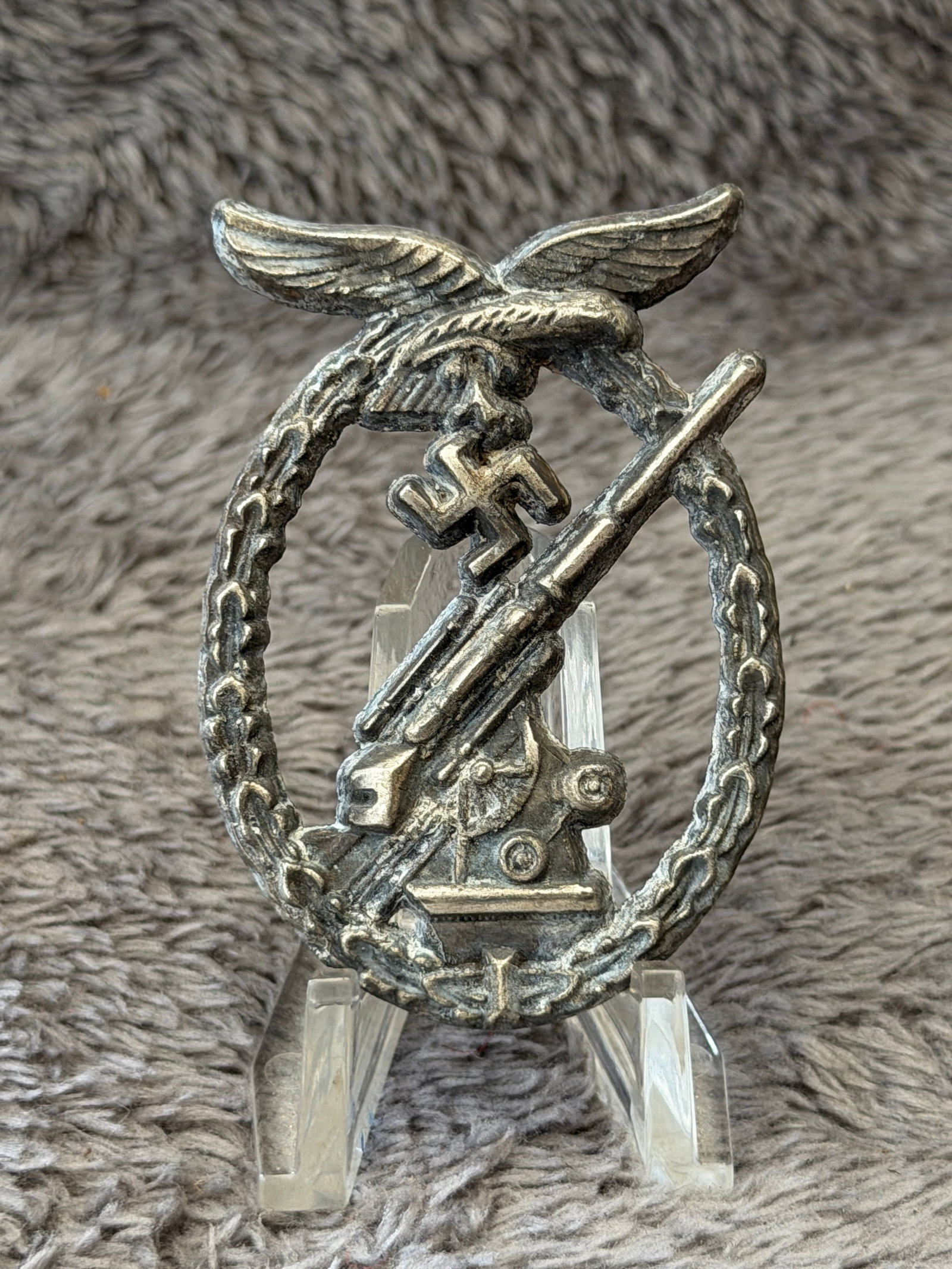 WWII German Luftwaffe Flak Anti-Aircraft War Badge: This WWII German Luftwaffe Flak Anti-Aircraft War Badge features the classic design of a Luftwaffe eagle clutching a swastika above an oak leaf wreath surrounding an anti-aircraft gun in firing positi
