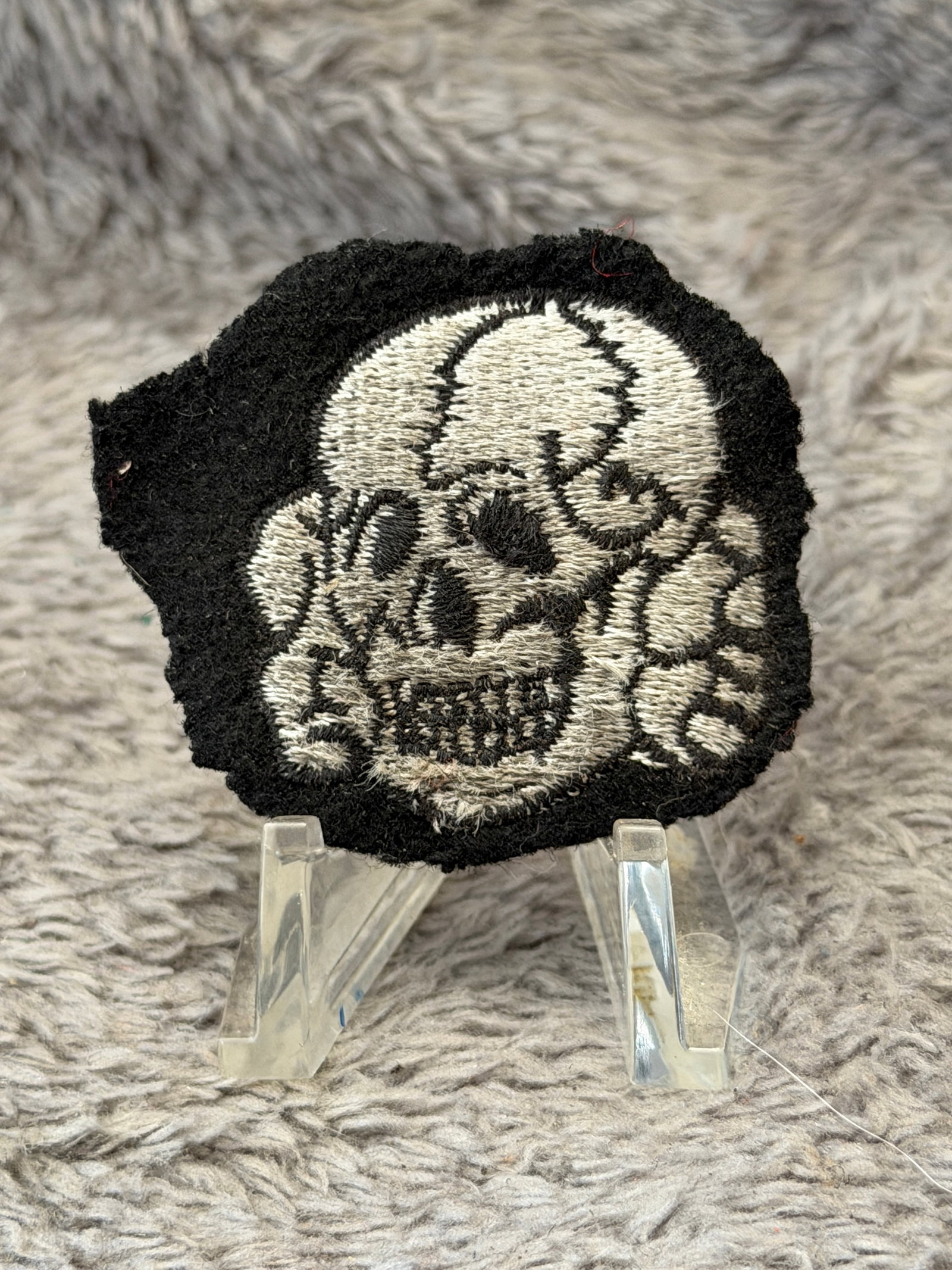 WWII German Waffen-SS Totenkopf Sleeve Insignia: This WWII German Waffen-SS Totenkopf Sleeve Insignia features the iconic embroidered skull and crossbones design executed in white thread on a black wool backing. The detailed Totenkopf displays well-