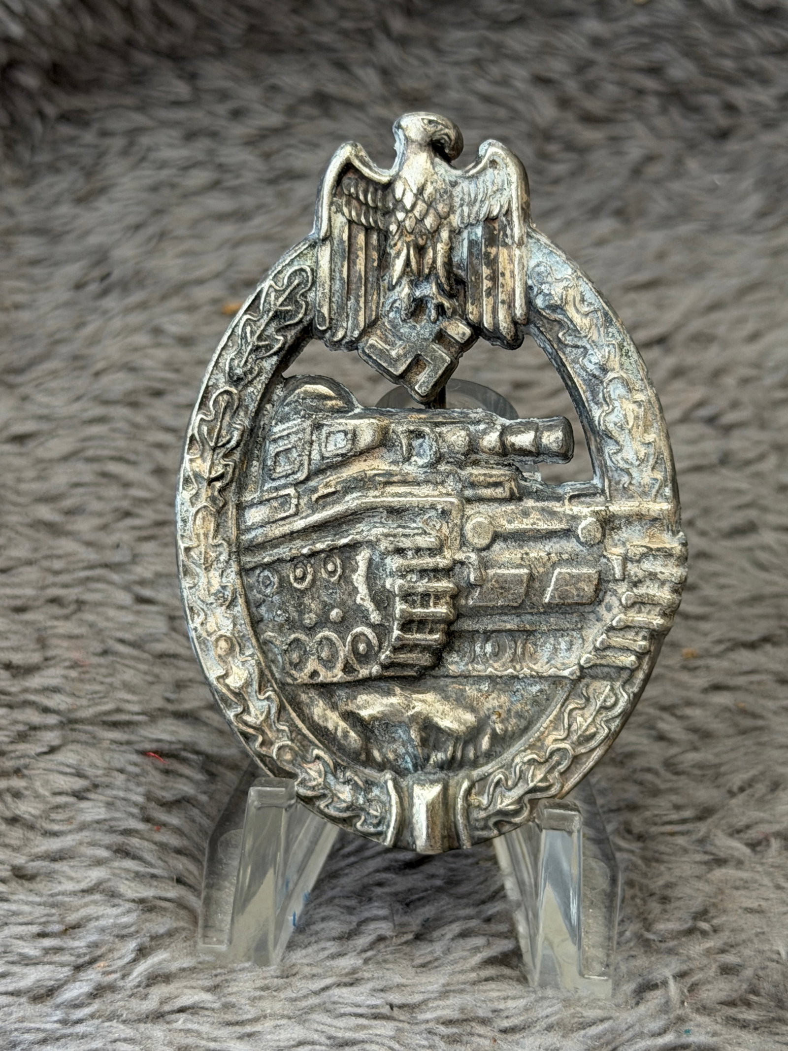 WWII German Panzer Assault Badge in Silver: This WWII German Panzer Assault Badge in Silver features the classic design of a Wehrmacht eagle clutching a swastika above an oval oak leaf wreath enclosing a detailed Panzer tank advancing over roug