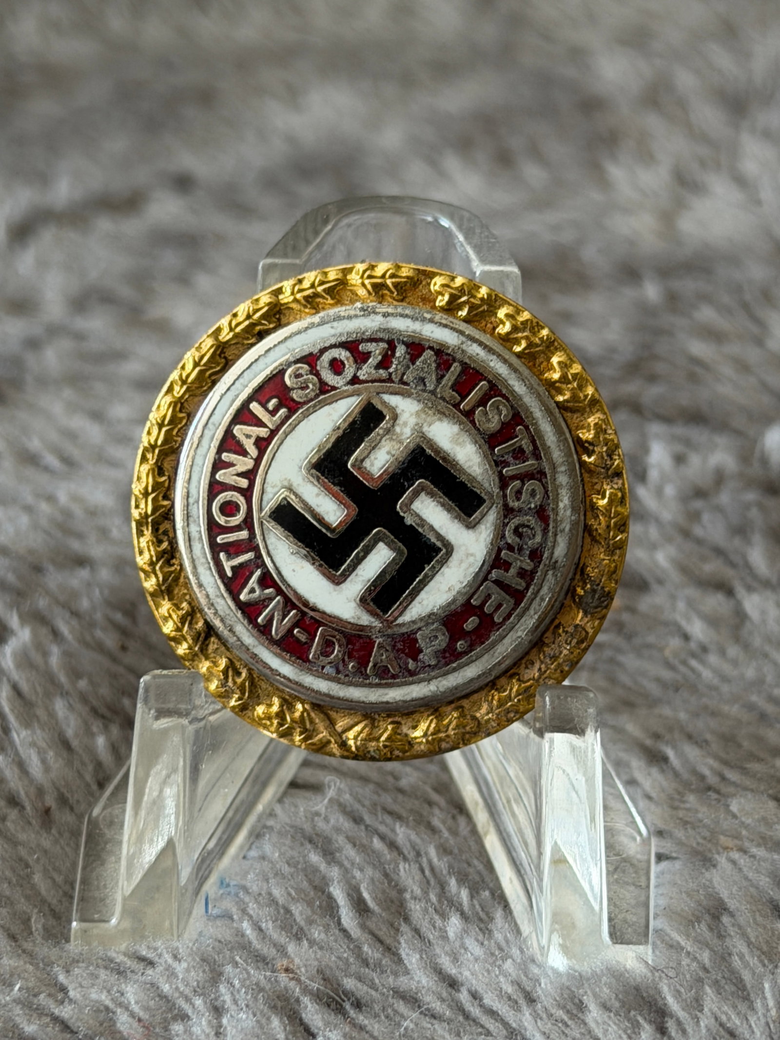 WWII German NSDAP Golden Party Badge No. 50569: This WWII German NSDAP Golden Party Badge features the iconic black swastika on a white enamel field surrounded by a red enamel ring inscribed "National-Sozialistische D.A.P.", all enclosed by a gilt 
