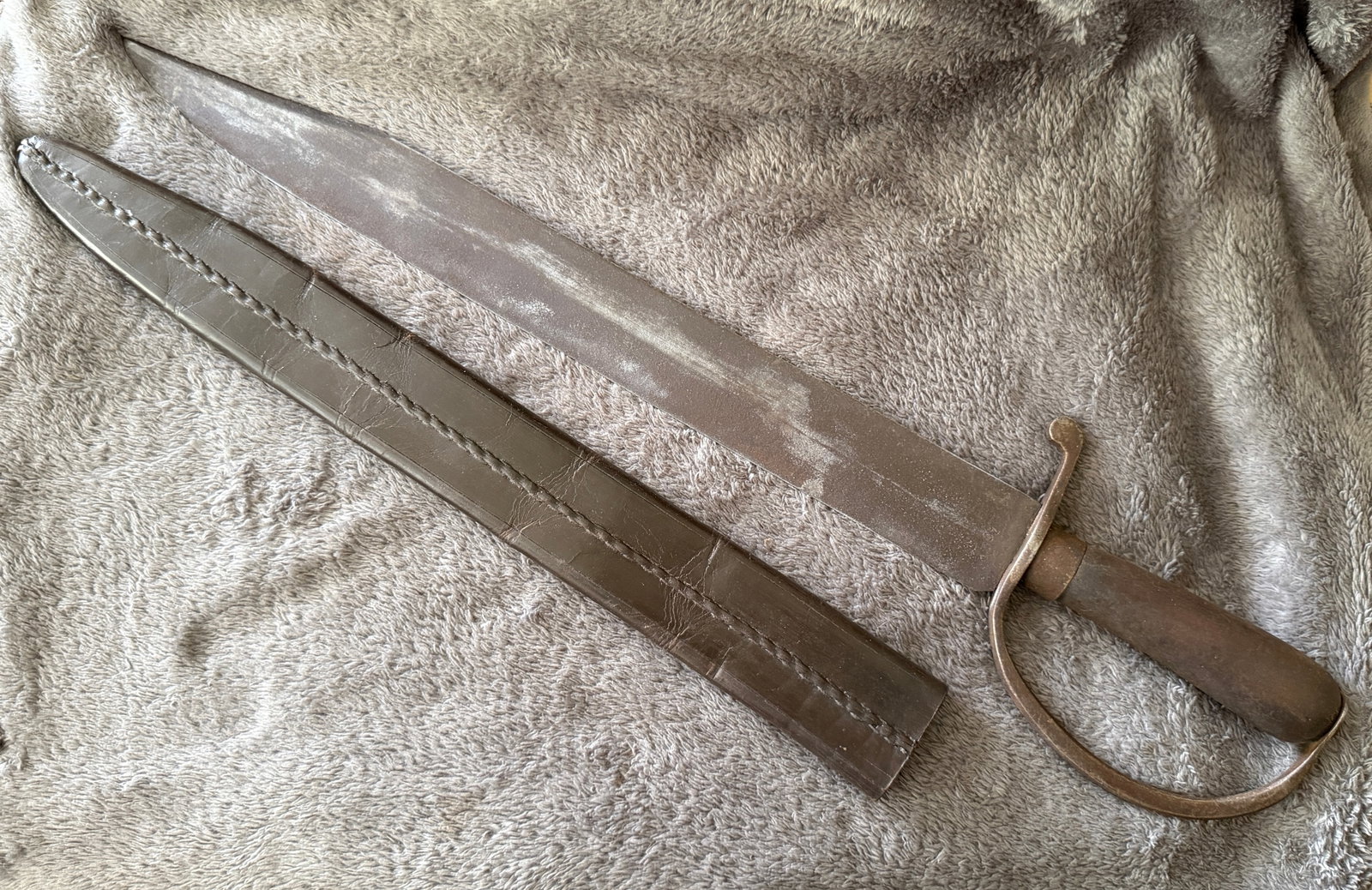 Civil War Large D-Guard Bowie Knife Dated 1861 Marked Macon Arsenal with Leather Scabbard: This formidable Civil War large D-Guard Bowie knife features a massive clipped-point blade, forged iron D-shaped hand guard, smooth hardwood grip, and its fitted brown leather scabbard. The ricasso is