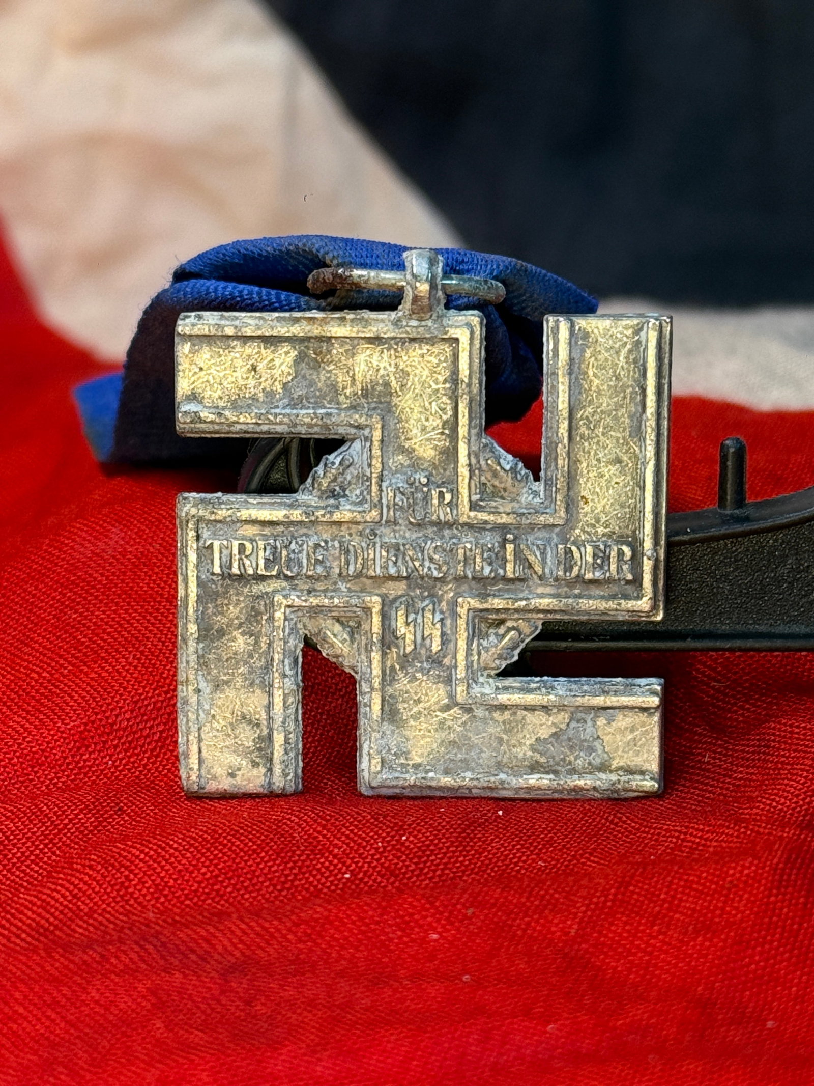 WWII German SS Treue Dienst Linder Service Medal – Blue Ribbon SS Runes: This German SS-related service decoration features a large geometric cross-form medal suspended from a blue ribbon. The front bears the inscription “FÜR TREUE DIENSTE LINDER” with SS runes po