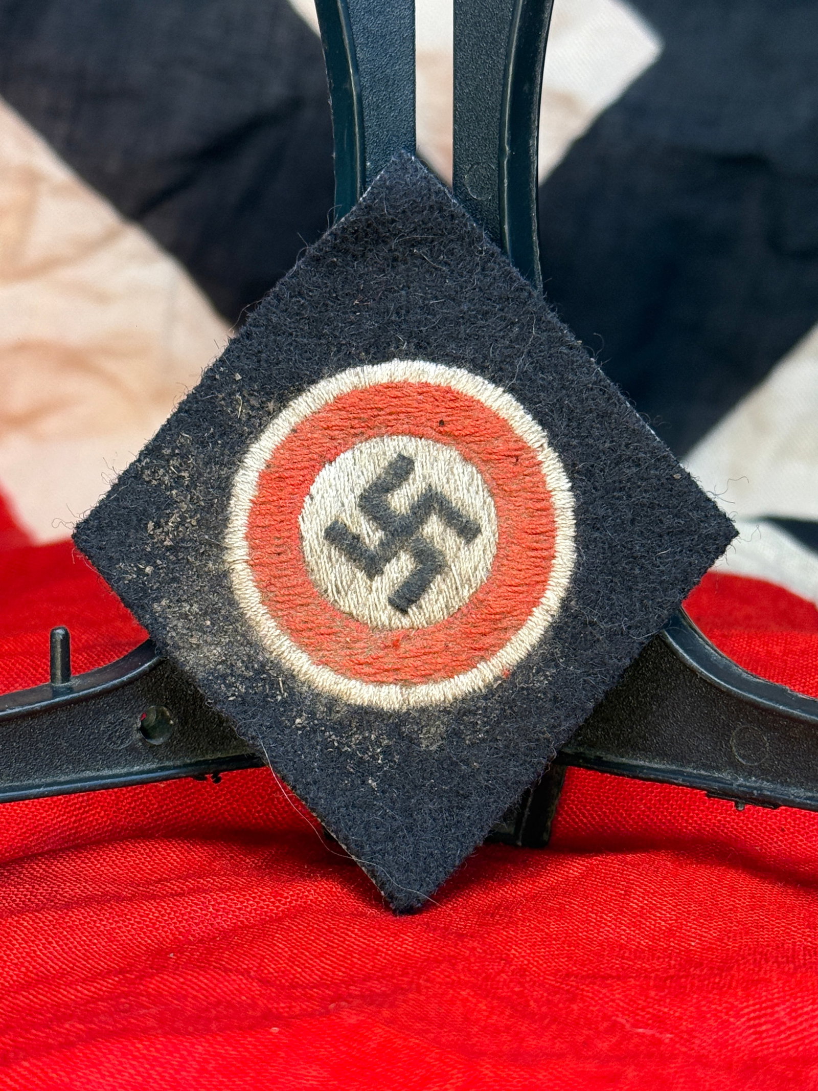 WWII German NSDAP Political Uniform Sleeve Insignia – Embroidered Swastika Wool Patch: This German political uniform insignia features a diamond-shaped black wool backing with a centrally embroidered circular emblem consisting of a black swastika on a white field surrounded by a red rin