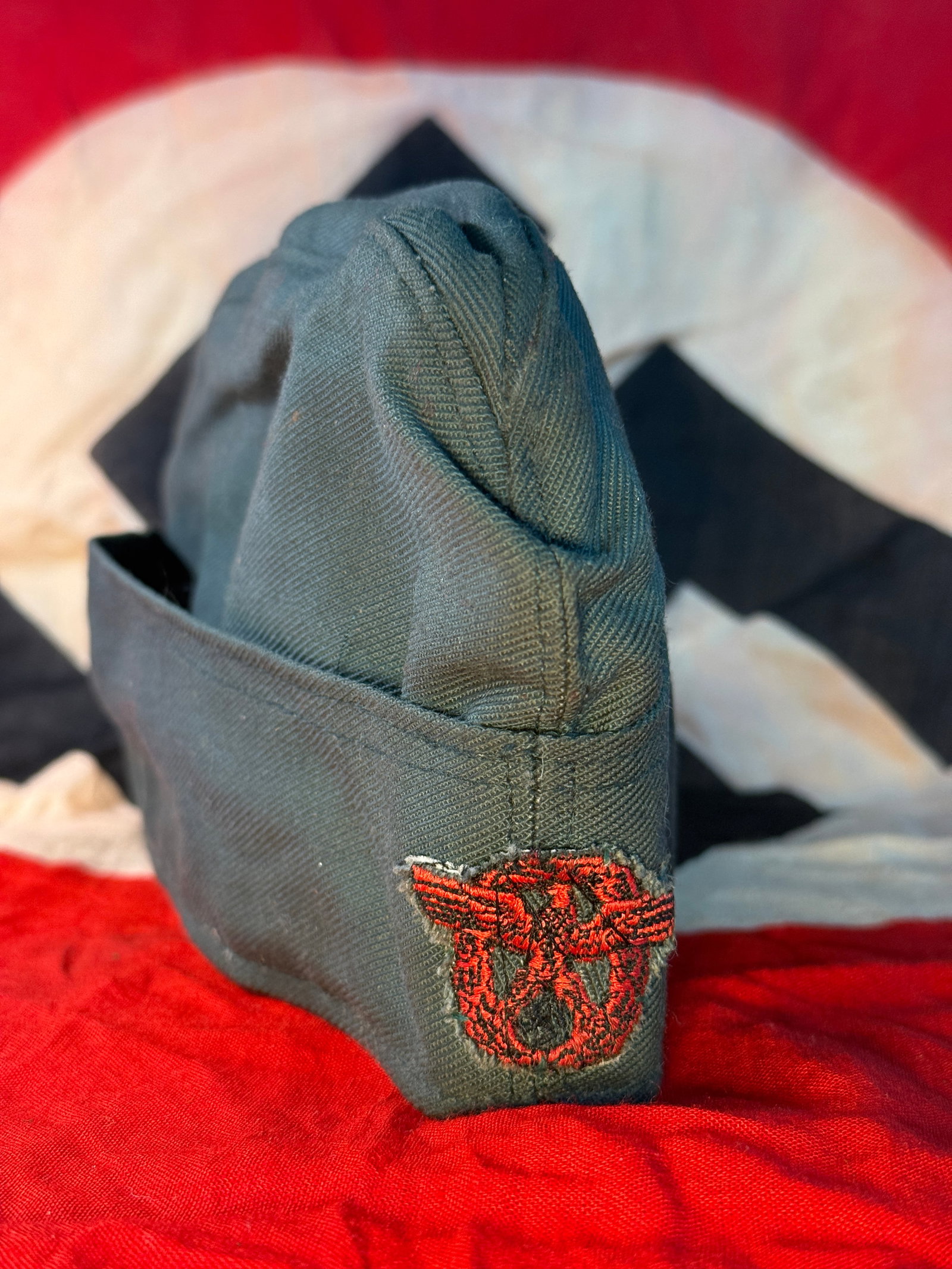 WWII German Political Leader Overseas Cap: This WWII German overseas cap is constructed of field-gray twill material and features a machine-embroidered red political eagle with swastika on the side panel, identifying it as a political organiza