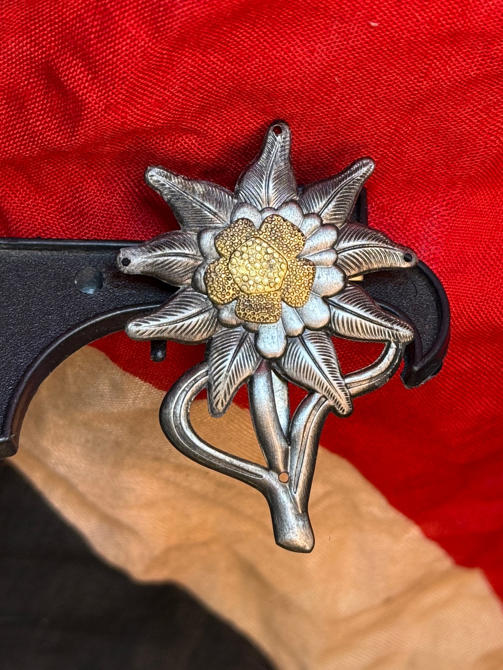 WWII German Gebirgsjäger Edelweiss Cap Insignia: This WWII German Gebirgsjäger Edelweiss insignia features the iconic alpine flower with finely detailed petals surrounding a textured center, mounted beneath a climbing rope motif. Worn by members of