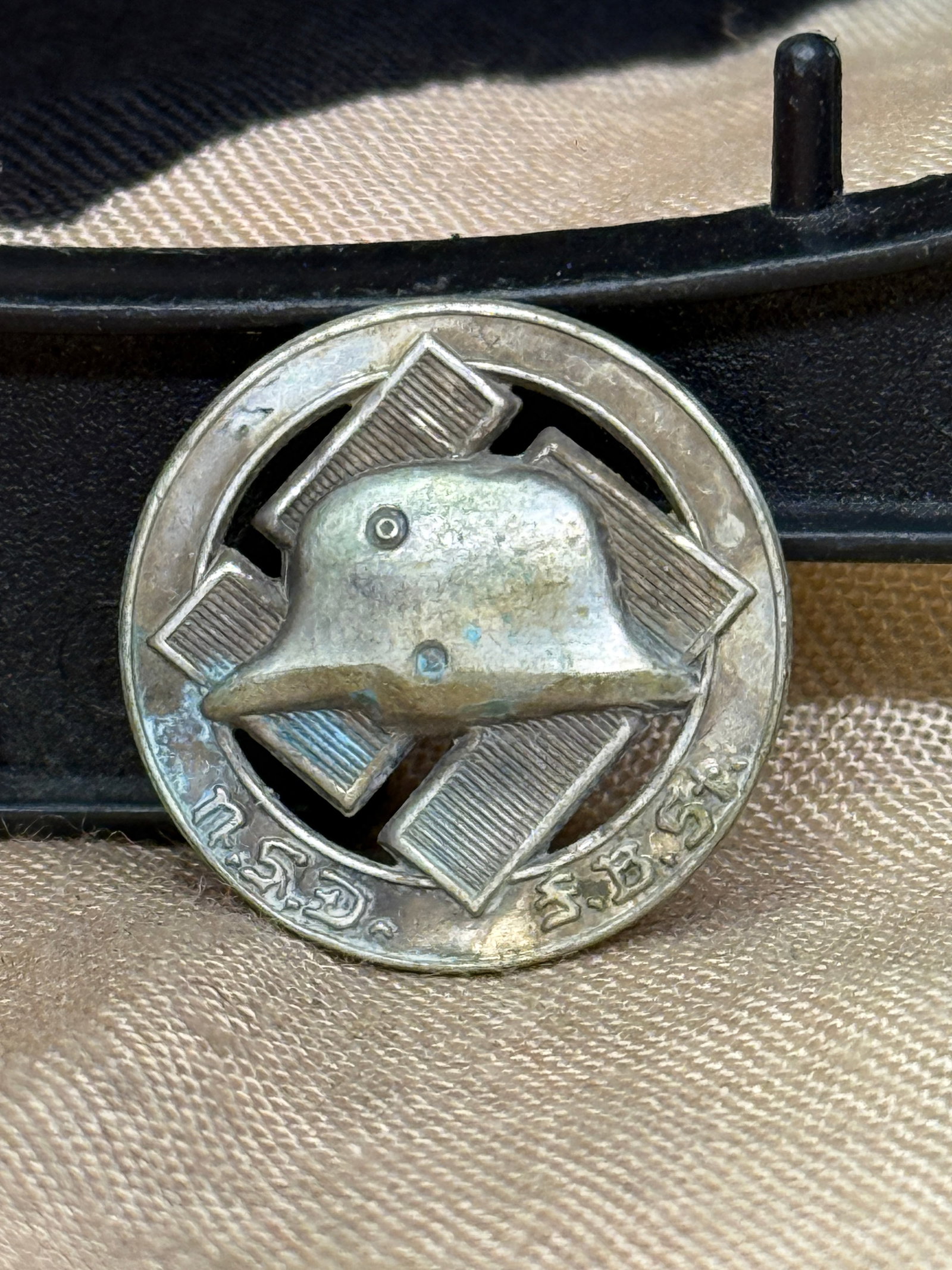 WWII German Stahlhelm Veteran Membership Badge: This circular German veteran's membership badge features a steel combat helmet superimposed over a stylized Iron Cross within an openwork circular frame. The reverse retains its original horizontal pi