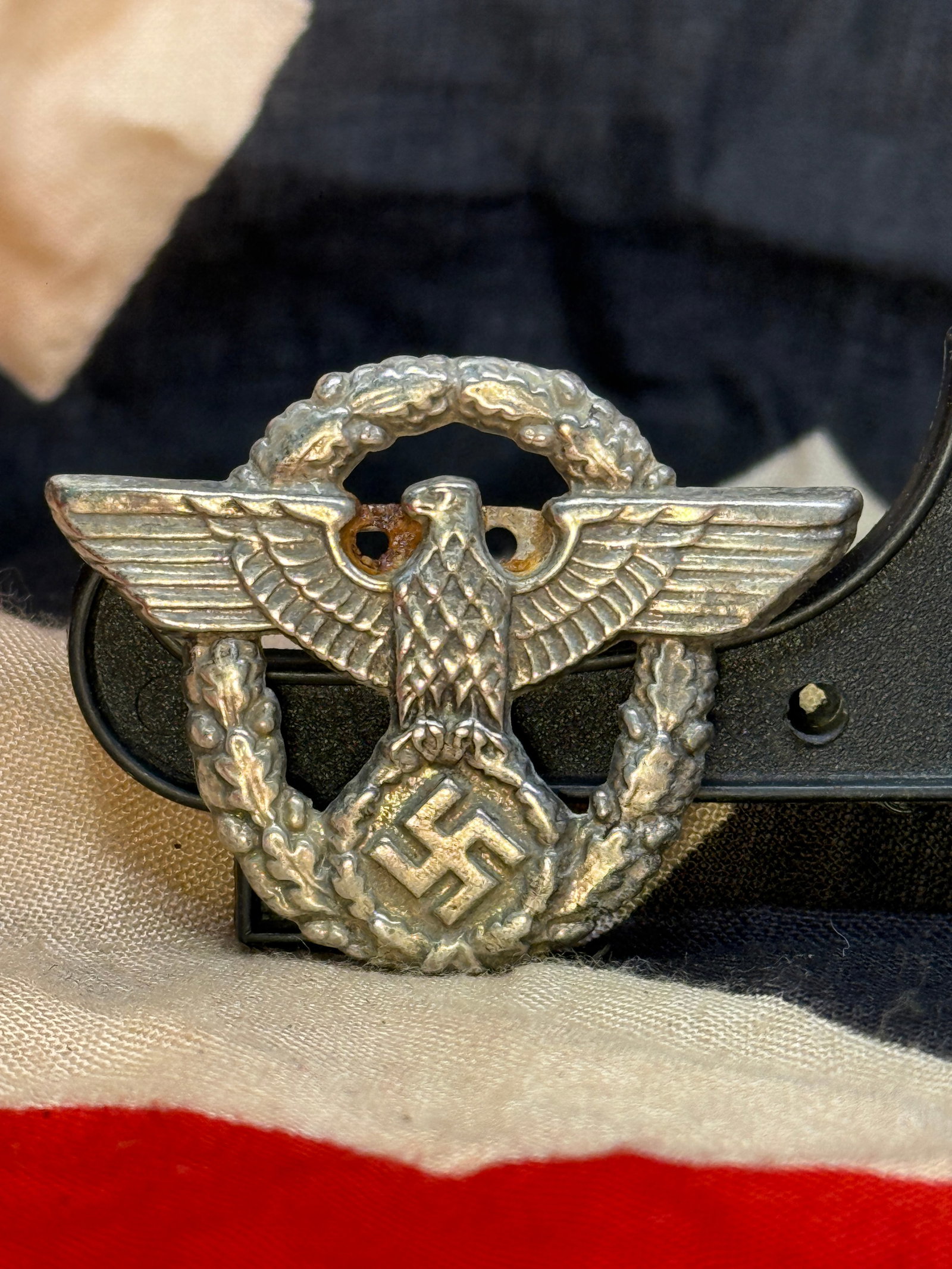WWII German Police Visor Cap Eagle Badge: This aluminum visor cap insignia features the outstretched national eagle clutching a wreathed swastika, the standard emblem worn on the visor caps of the Ordnungspolizei (Order Police) and related Ge