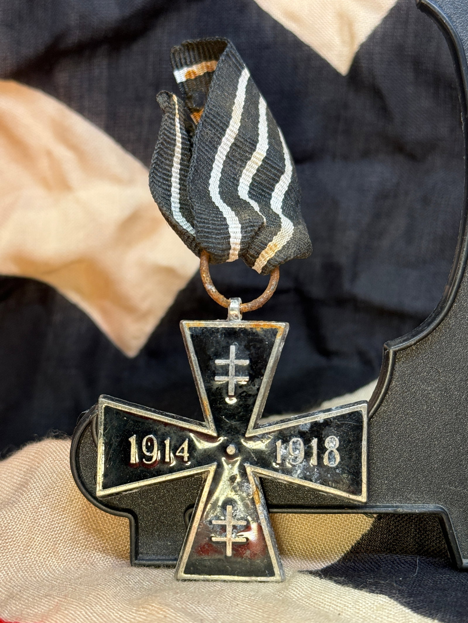 WWI German Honor Cross 1914–1918 Medal: This blackened cross-shaped decoration bears the dates "1914" and "1918" on the obverse with crossed swords, suspended from its original black, white, and red ribbon. Instituted to commemorate service