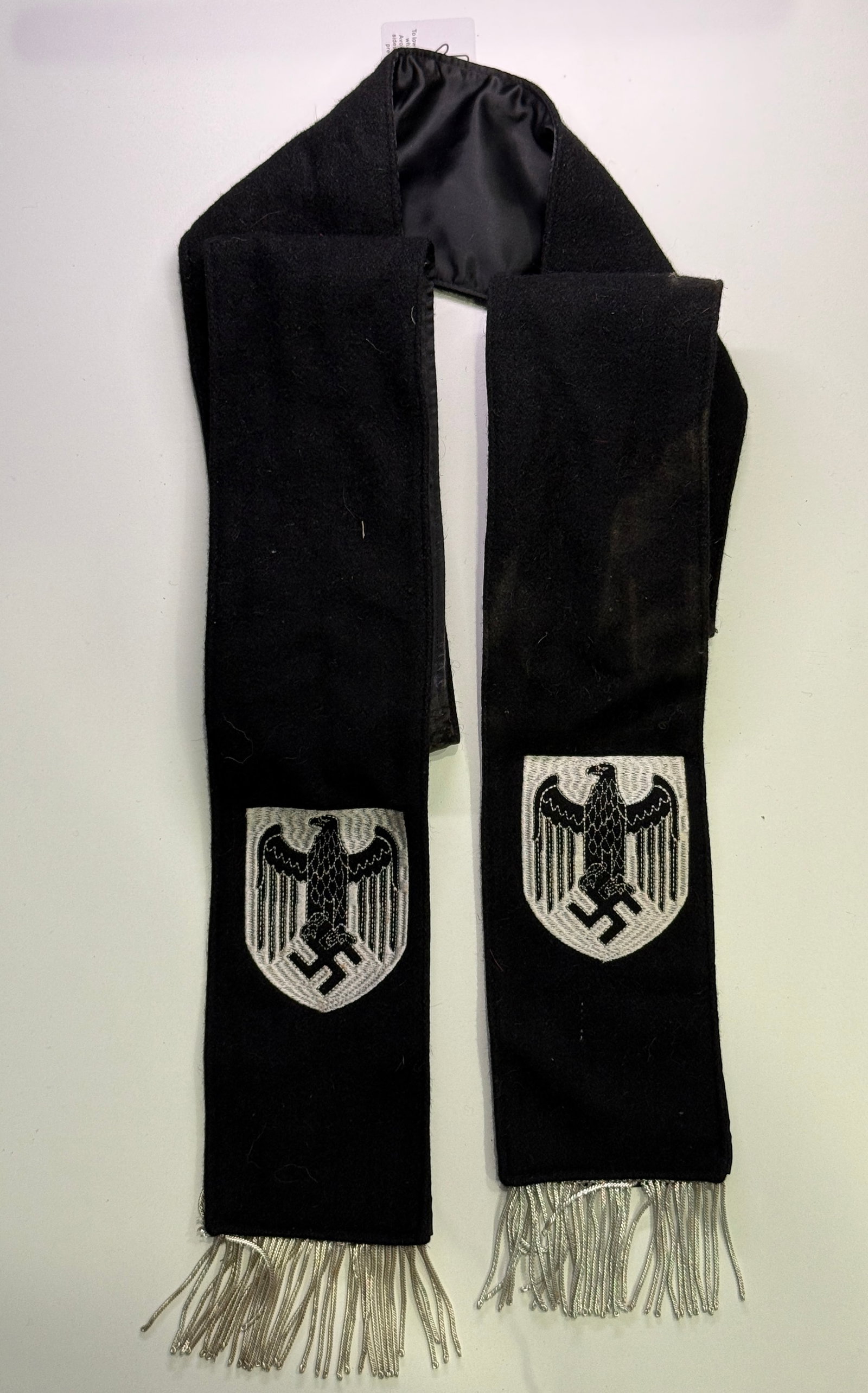 WWII German Wehrmacht Funeral or Memorial Wreath Sash: Long black mourning sash formed from a wool or felt-like outer fabric with a glossy black satin lining. Each broad hanging end bears a separately applied silver-gray woven shield displaying the German