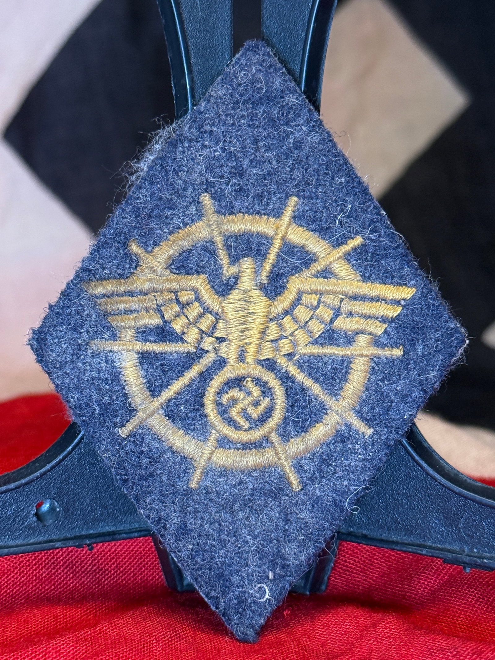 WWII German NSKK Motor Transport Sleeve Insignia: Diamond-shaped blue-gray wool uniform insignia associated with the Nationalsozialistisches Kraftfahrkorps, or National Socialist Motor Corps. The face is embroidered in golden-tan thread with a comple