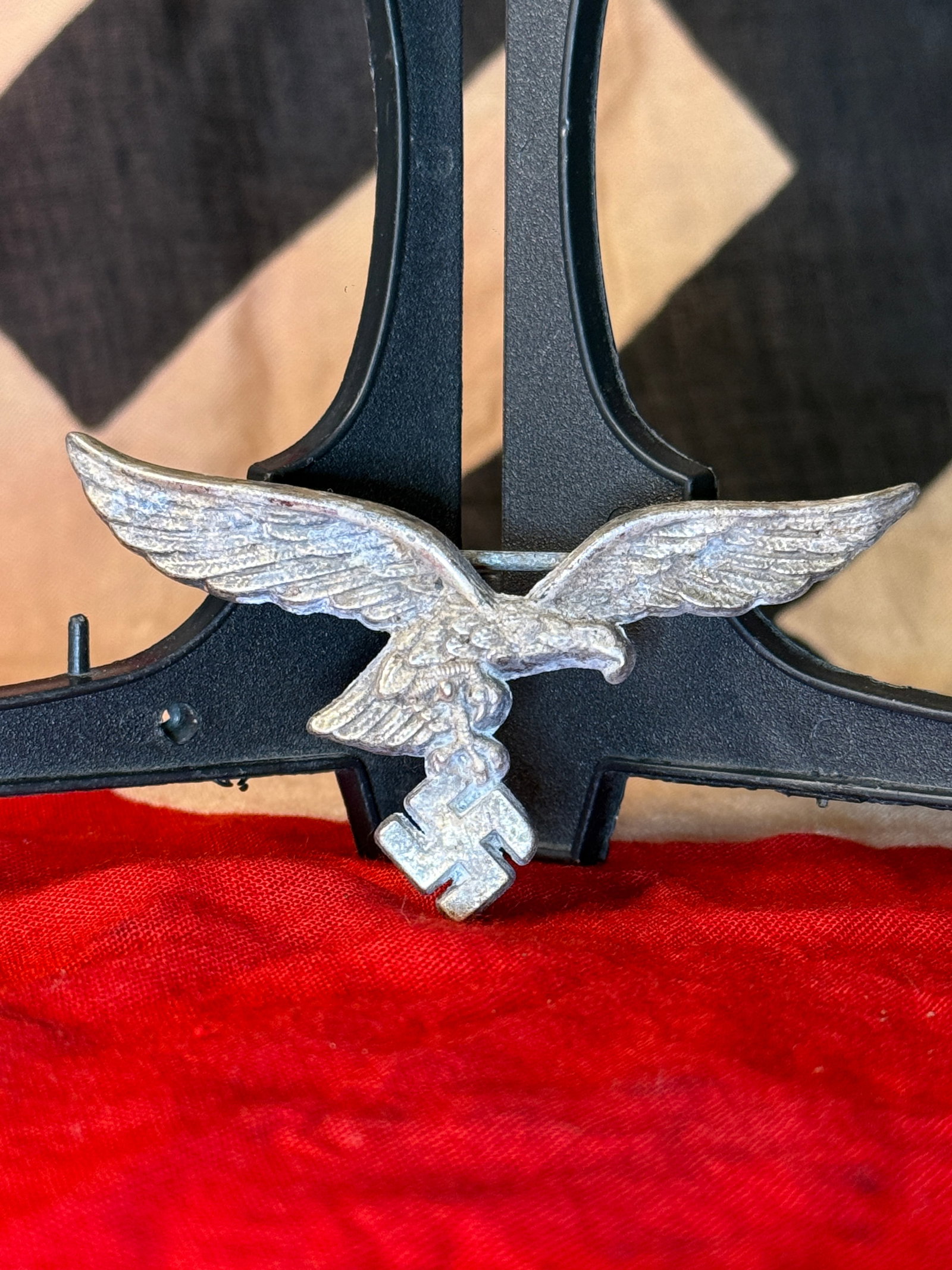 WWII German Luftwaffe-Style Visor-Cap Eagle Badge: Silver-colored metal insignia formed as a Luftwaffe eagle with outstretched wings, clutching a swastika in its talons. The sculpted front incorporates individually defined wing feathers, a lowered eag