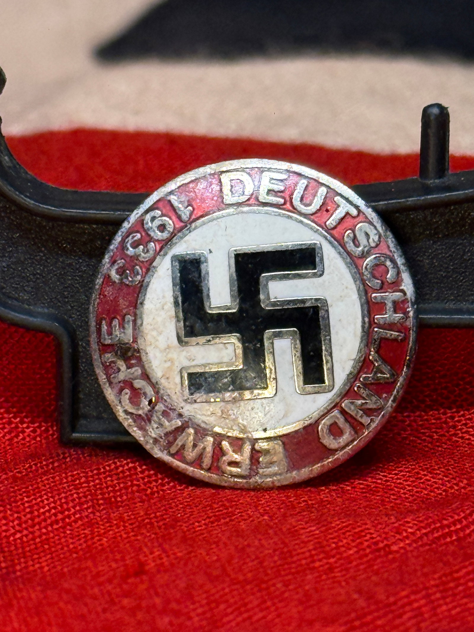 German Third Reich NSDAP-Related “Deutschland Erwache?? Enamel Badge, RZM M1/129 Marked: Circular metal and enamel badge displaying a black swastika within a white central field, surrounded by a red outer band bearing a partially worn German inscription that includes “Deutschland Erwach