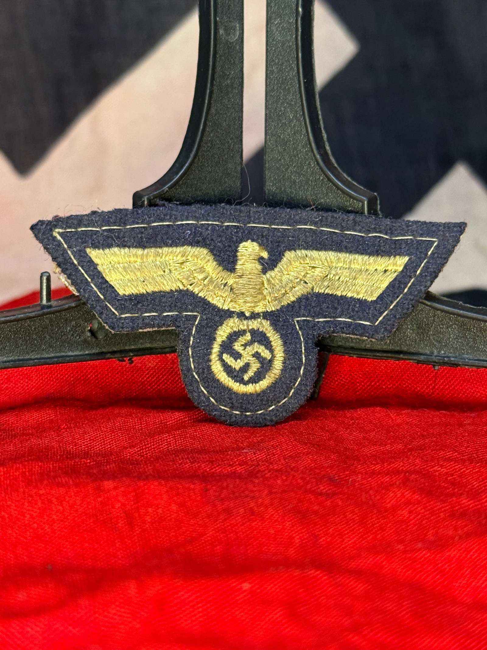 WWII German Kriegsmarine Gold-Embroidered Breast Eagle: German naval uniform insignia embroidered in golden-yellow thread on a dark navy-blue wool backing. The design consists of a horizontally spread national eagle above a circular wreath enclosing a swas