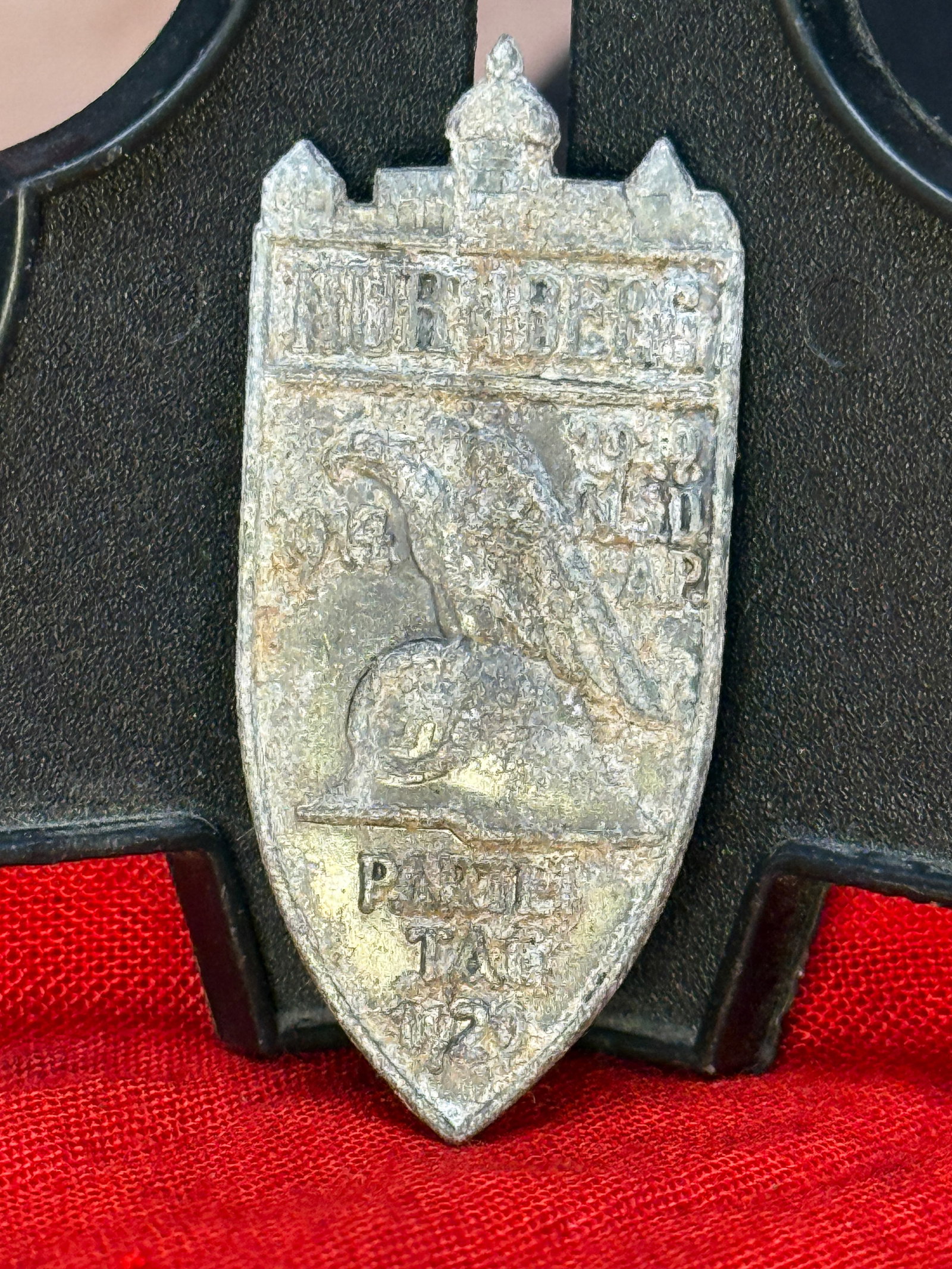German 1929 Nürnberg NSDAP Party Day Badge: Shield-shaped metal badge commemorating the 1929 National Socialist Party rally at Nürnberg. The face depicts Nürnberg’s historic city architecture above a helmeted profile, accompanied by partial