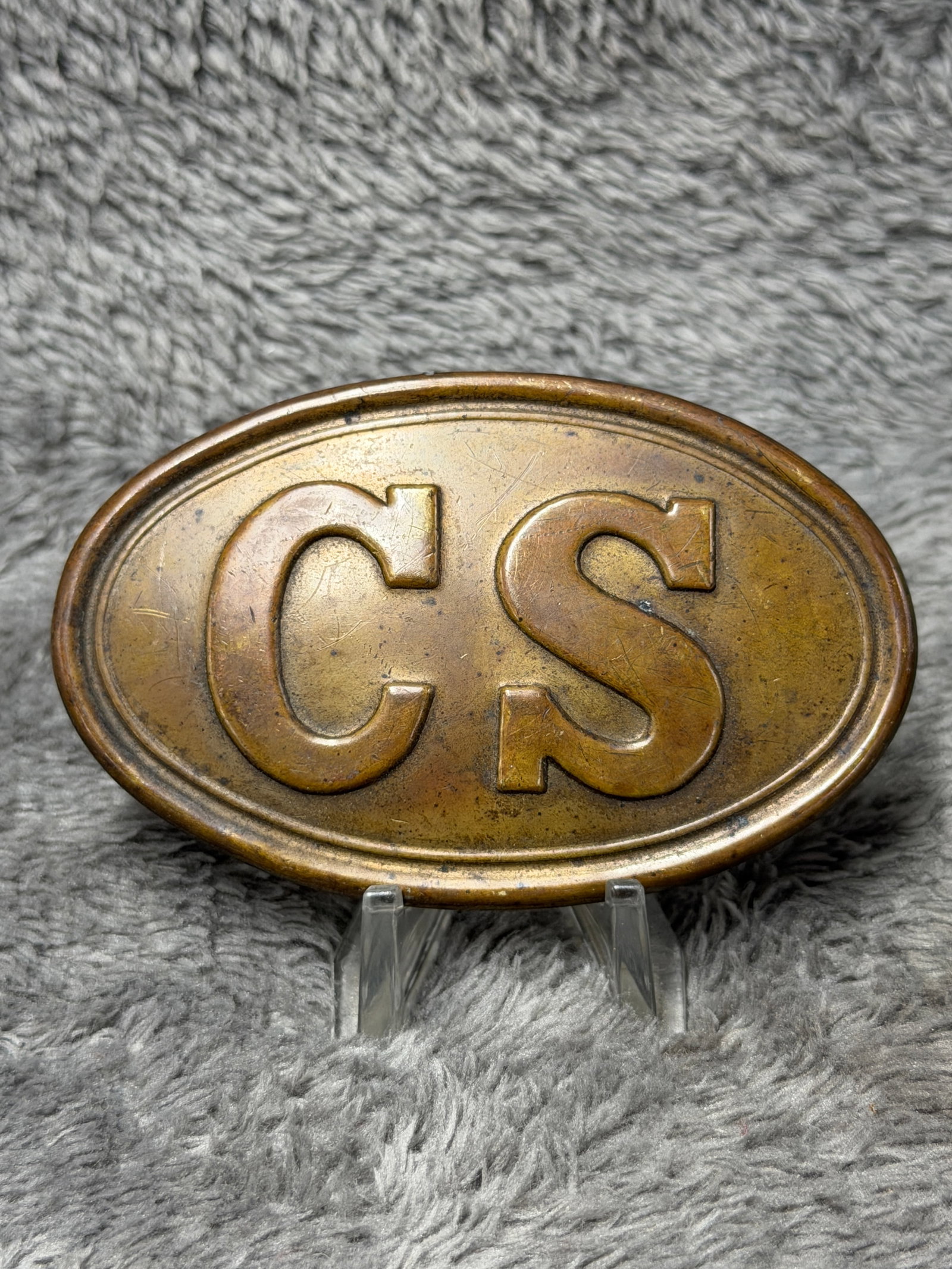 C.S. Confederate States Oval Brass Cartridge Box Plate Civil War Style: Oval brass-toned cartridge box plate featuring large raised “CS” lettering on the face, surrounded by a double-line oval border and rolled outer edge. The reverse has a silver-gray metal backi