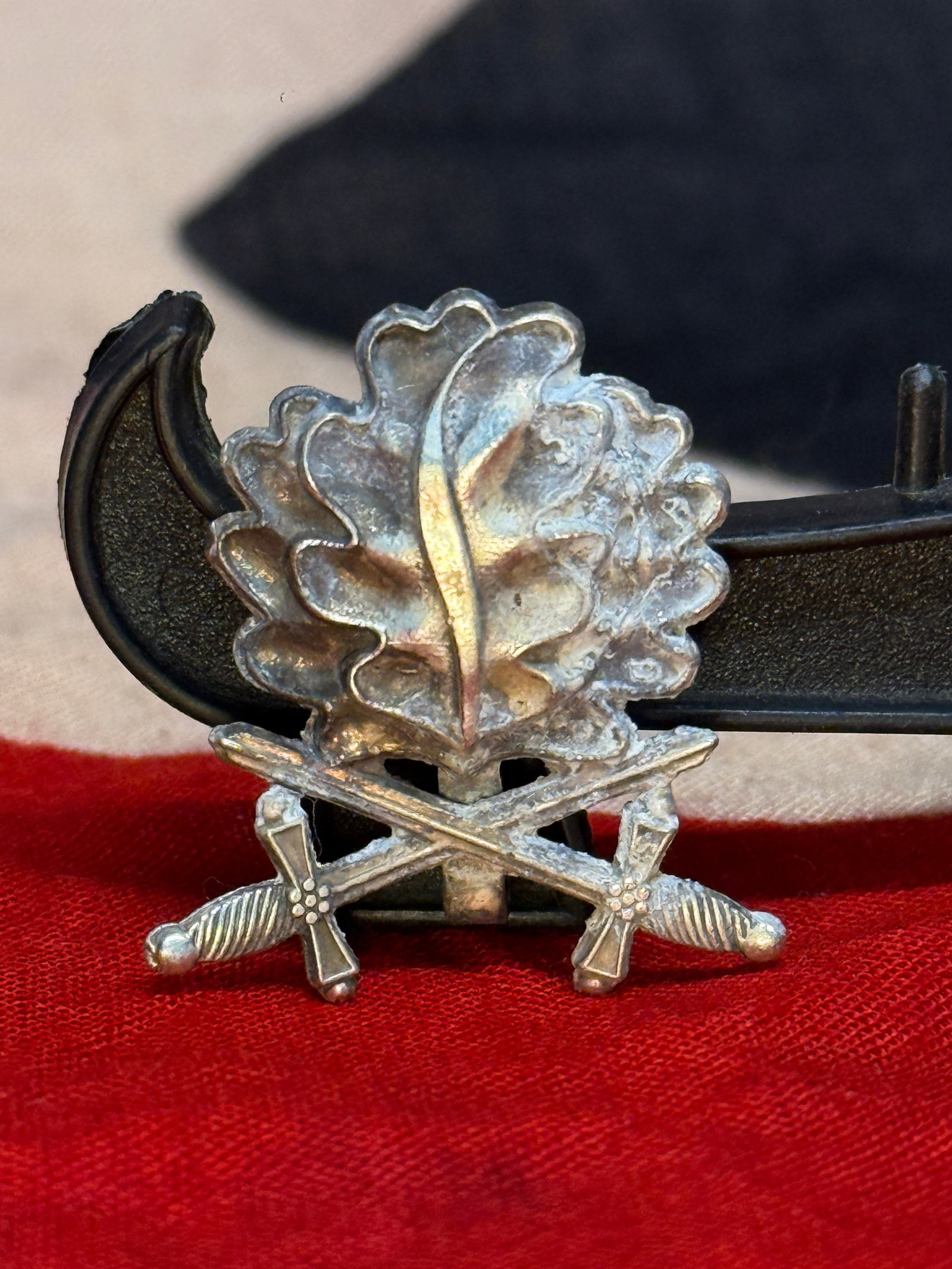 WW2 German 900 Silver Oak Leaf and Crossed-Swords Military Association Badge: Silver-grade badge formed as a spray of oak leaves surmounted by a vertical sword and crossed swords below. The reverse is maker-marked “ST&L,” stamped “800,” and carries the German si