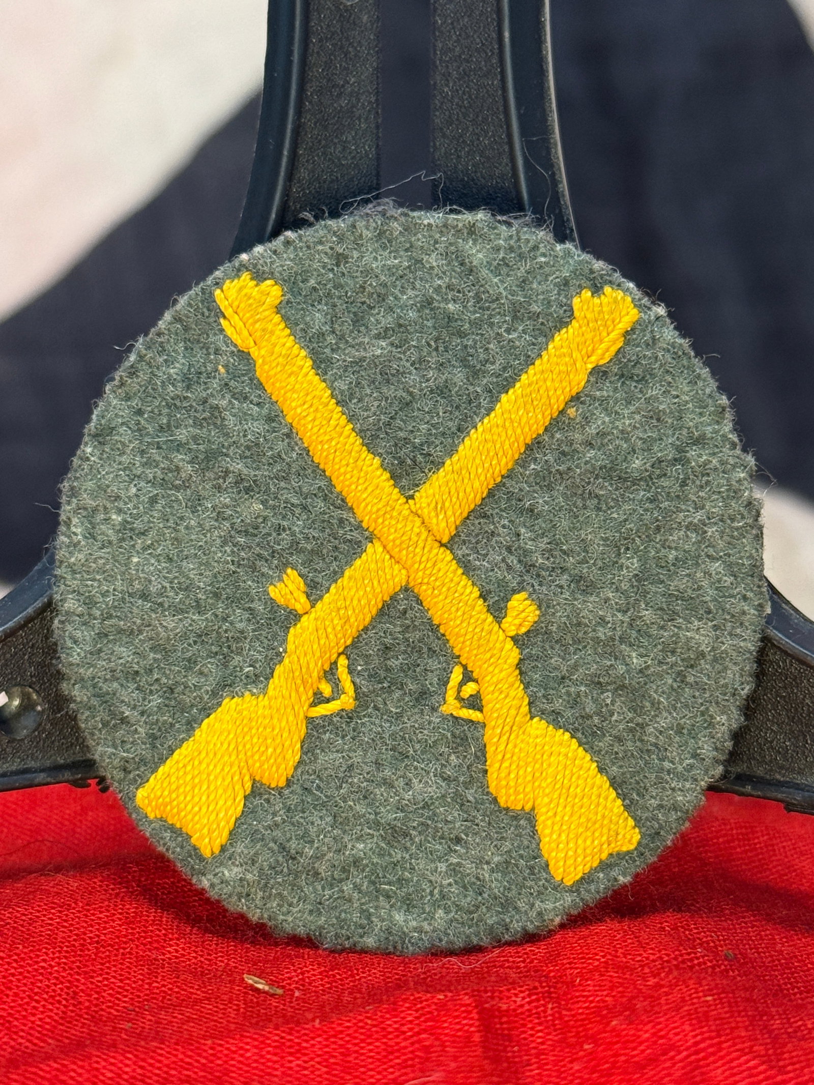 WWII German Infantry Trade Sleeve Patch: This circular wool trade insignia displays a pair of crossed rifles embroidered in golden-yellow thread against a field-gray wool backing. Worn on the sleeve of Wehrmacht uniforms, insignia of this st