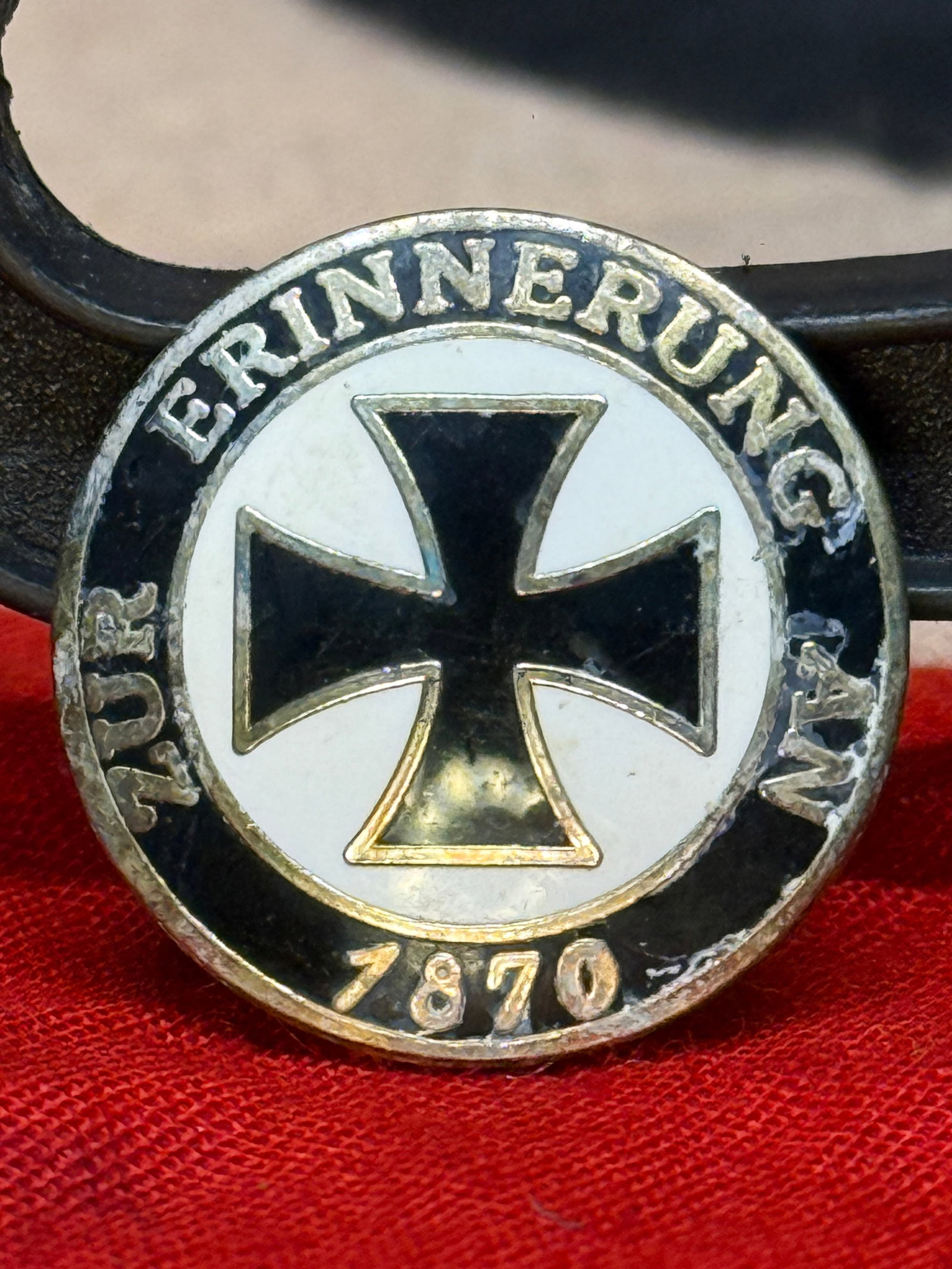 German Franco-Prussian War 1870 "Erinnerung an 1870" Veterans Pin: This circular commemorative pin features the black Iron Cross within a white enamel field surrounded by the inscription "Erinnerung an 1870" ("Remembrance of 1870"), honoring veterans of the Franco-Pr