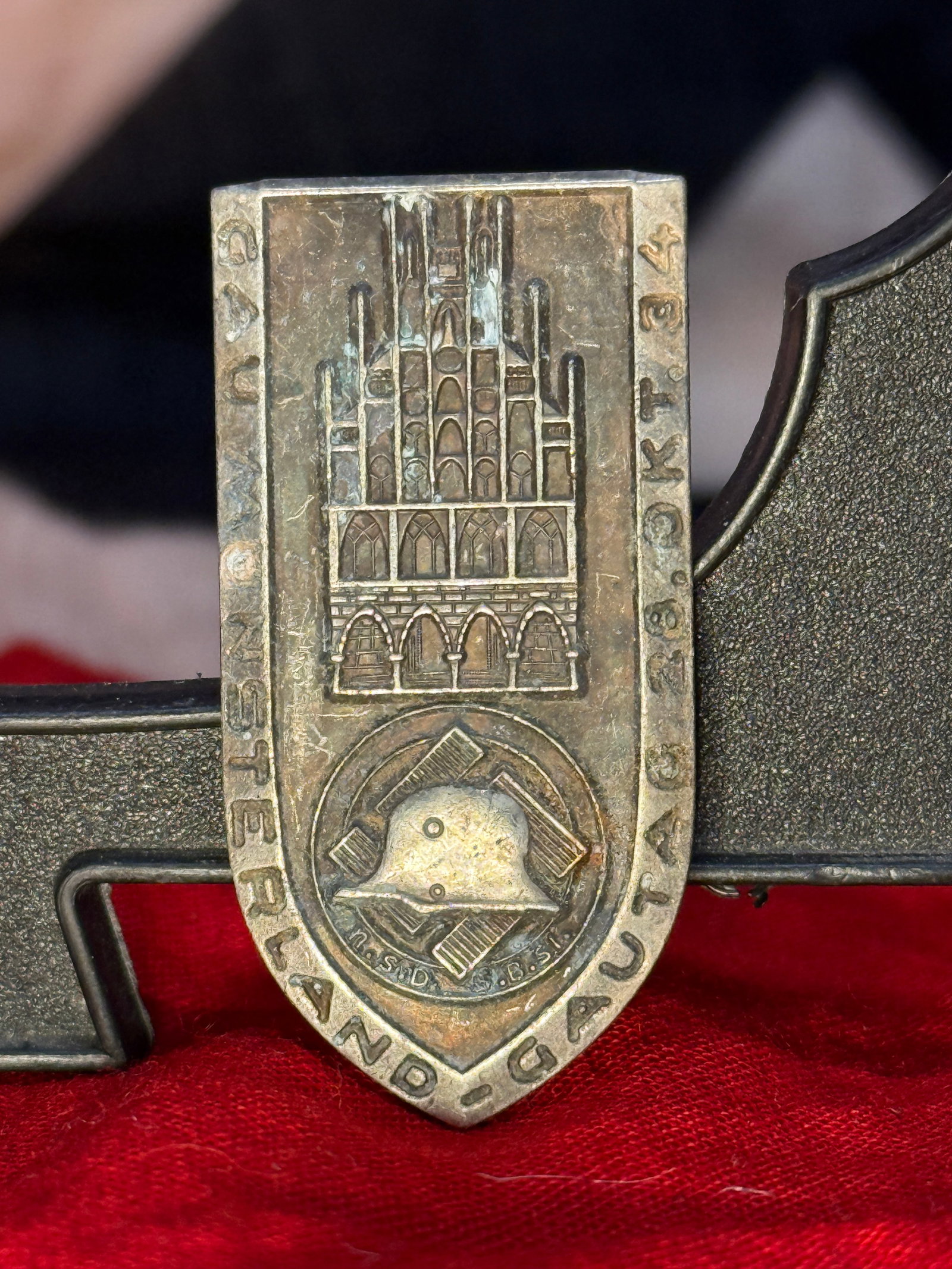 WWII German Westland 1942 Tinnie: This silvered commemorative tinnie depicts a Gothic-style cathedral above a steel helmet set within a cogwheel, surrounded by the inscription "WESTLAND-TAGUNG 1942." The reverse retains its original h
