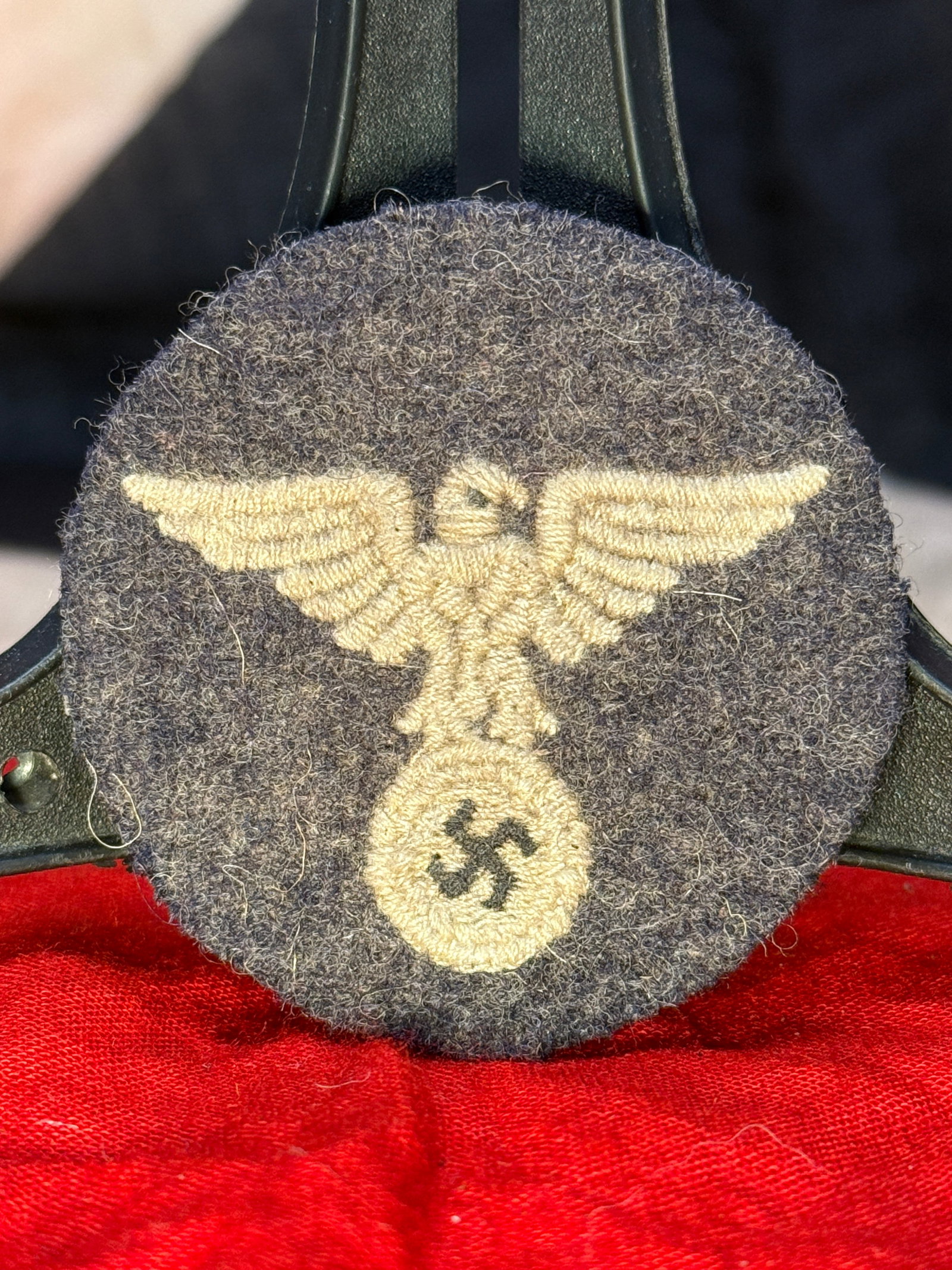 WWII German Kriegsmarine Sleeve Eagle Insignia: This circular dark gray wool patch features an embroidered national eagle clutching a wreath enclosing a swastika, identifying it as a Kriegsmarine sleeve eagle insignia from World War II. Executed in