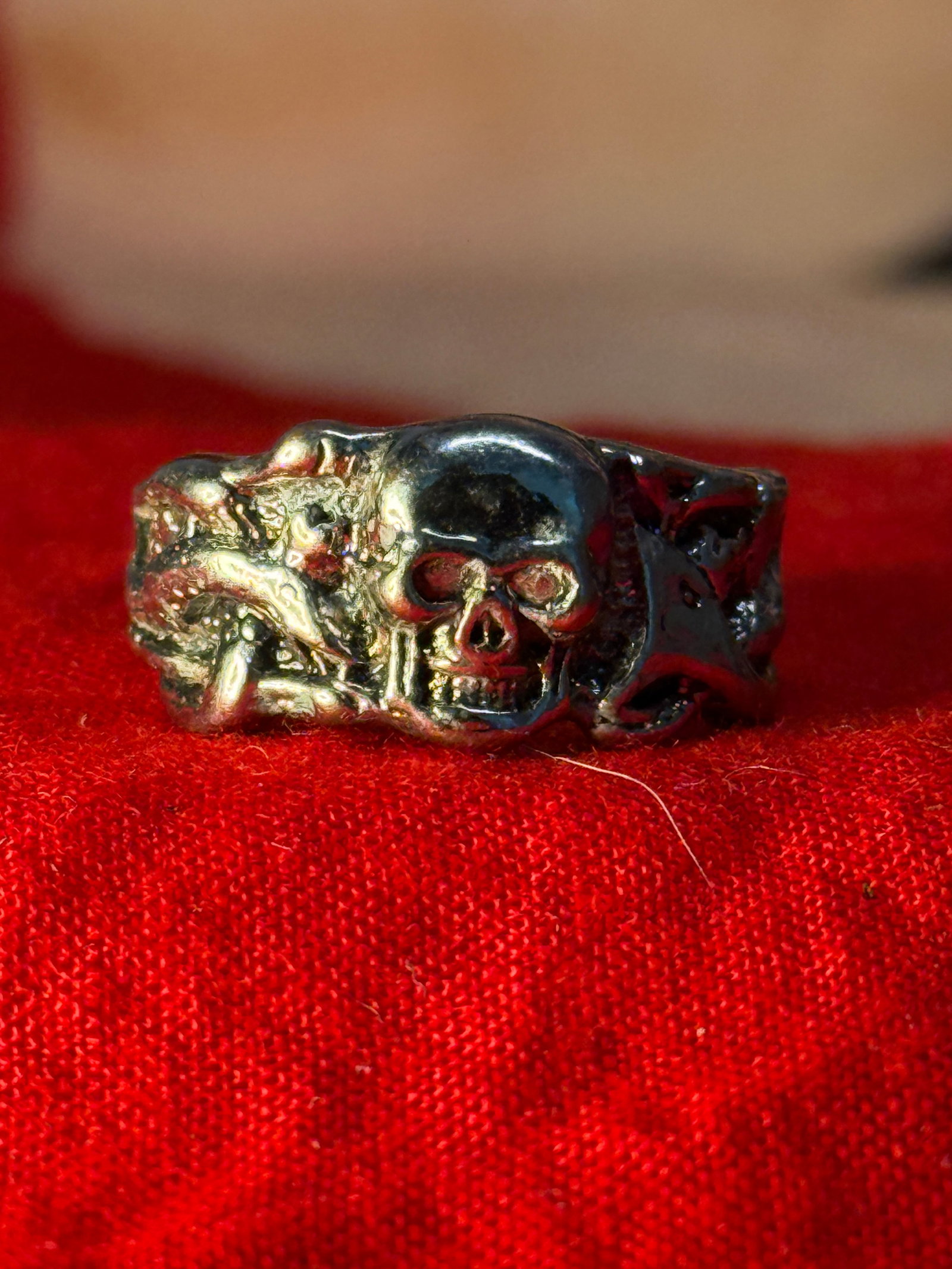 WWII German Totenkopf Silver Skull Ring: This cast metal ring features a prominent Totenkopf (Death's Head) skull flanked by sculpted skeletal motifs that continue around the shoulders of the band. The openwork construction and detailed reli