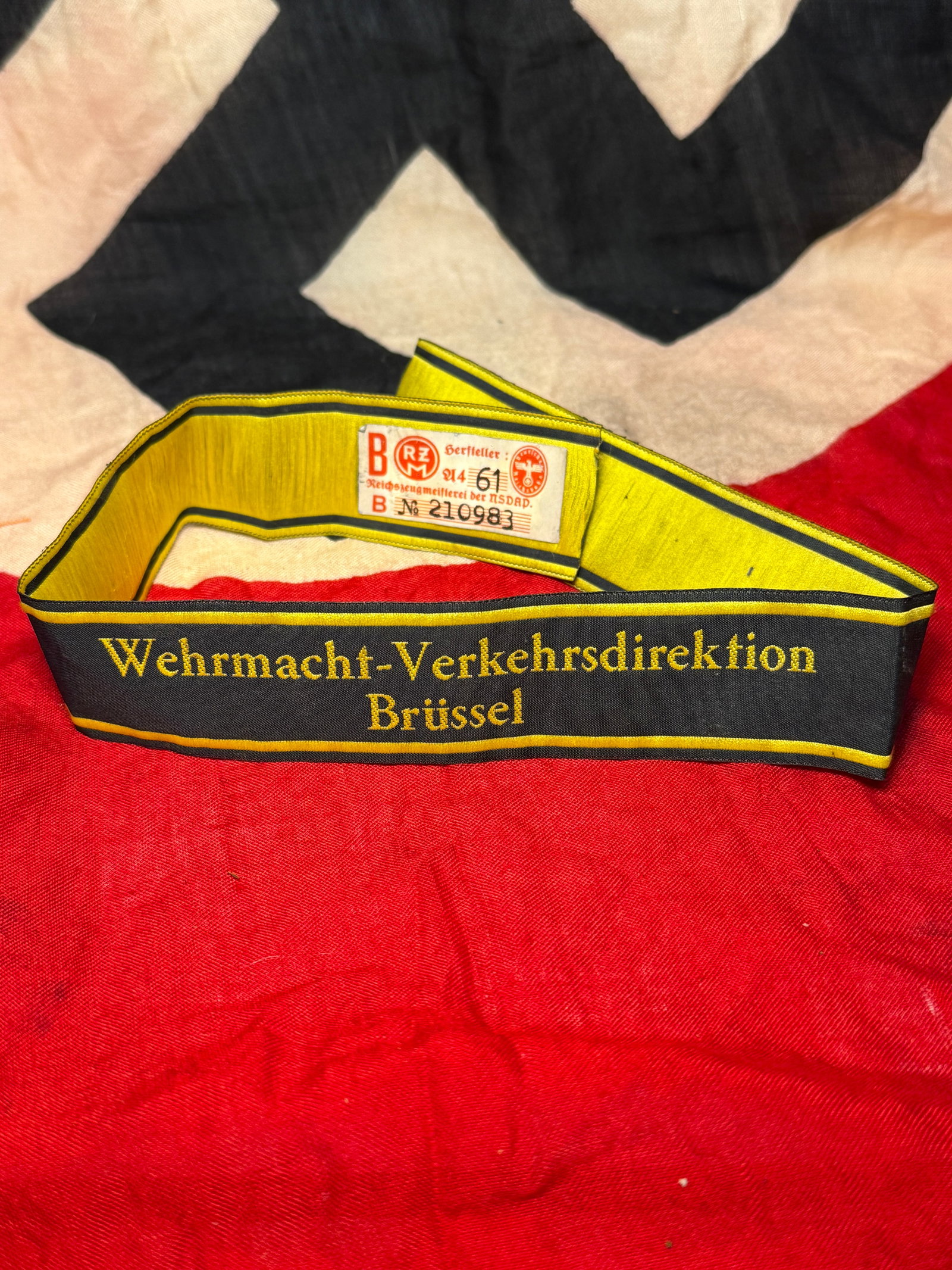 WWII German Wehrmacht-Verkehrsdirektion Brüssel Cuff Title With RZM Paper Tag: This WWII German Wehrmacht-Verkehrsdirektion Brüssel cuff title is woven in black with yellow lettering and borders, identifying service with the Wehrmacht Transportation Directorate in Brussels duri