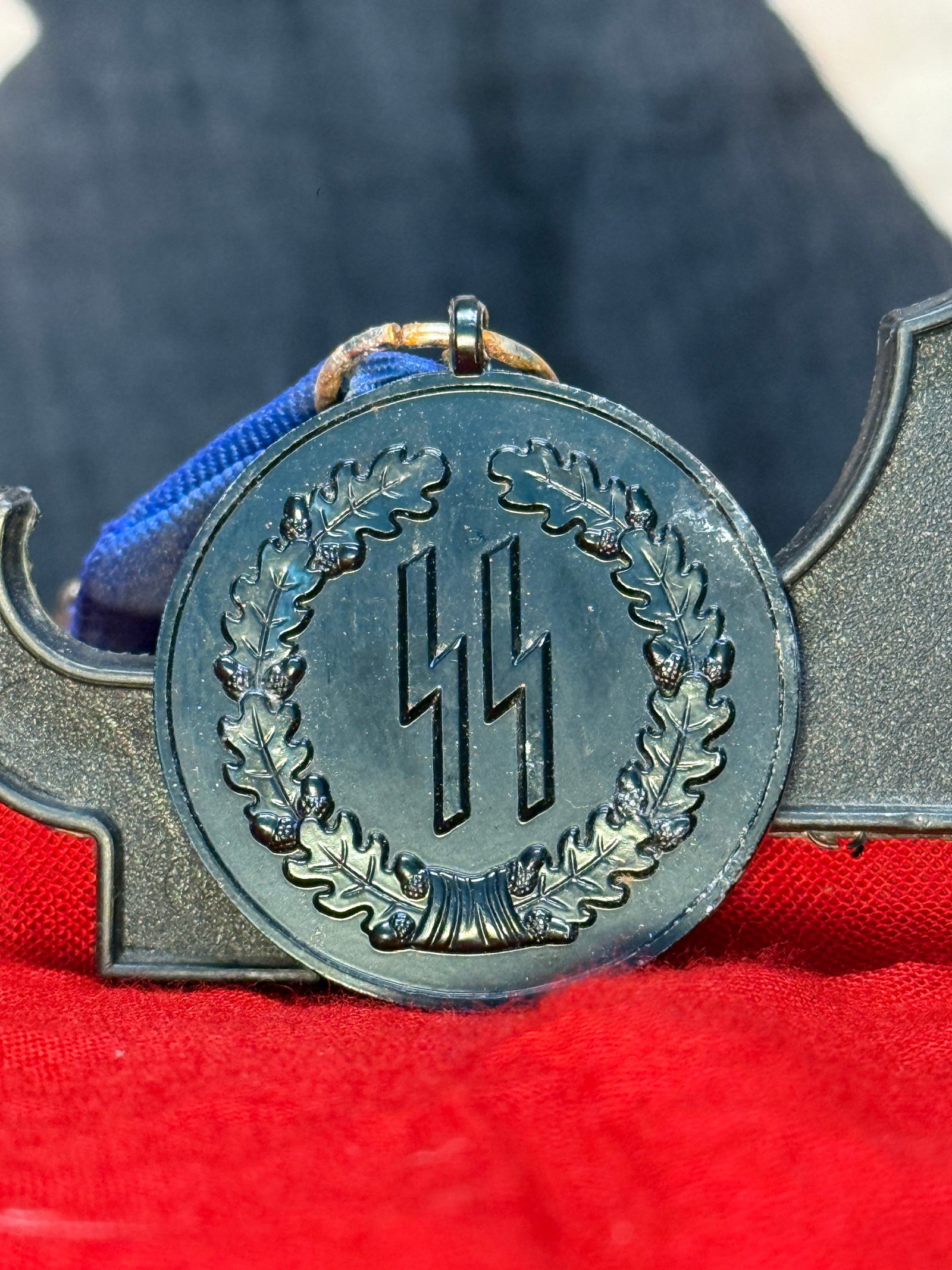 WWII German Waffen-SS 4-Year Long Service Medal With Blue Ribbon: This Waffen-SS 4-Year Long Service Medal features the distinctive SS runes within an oak leaf wreath on the obverse, while the reverse bears the inscription "Für Treue Dienste in der SS" over the num