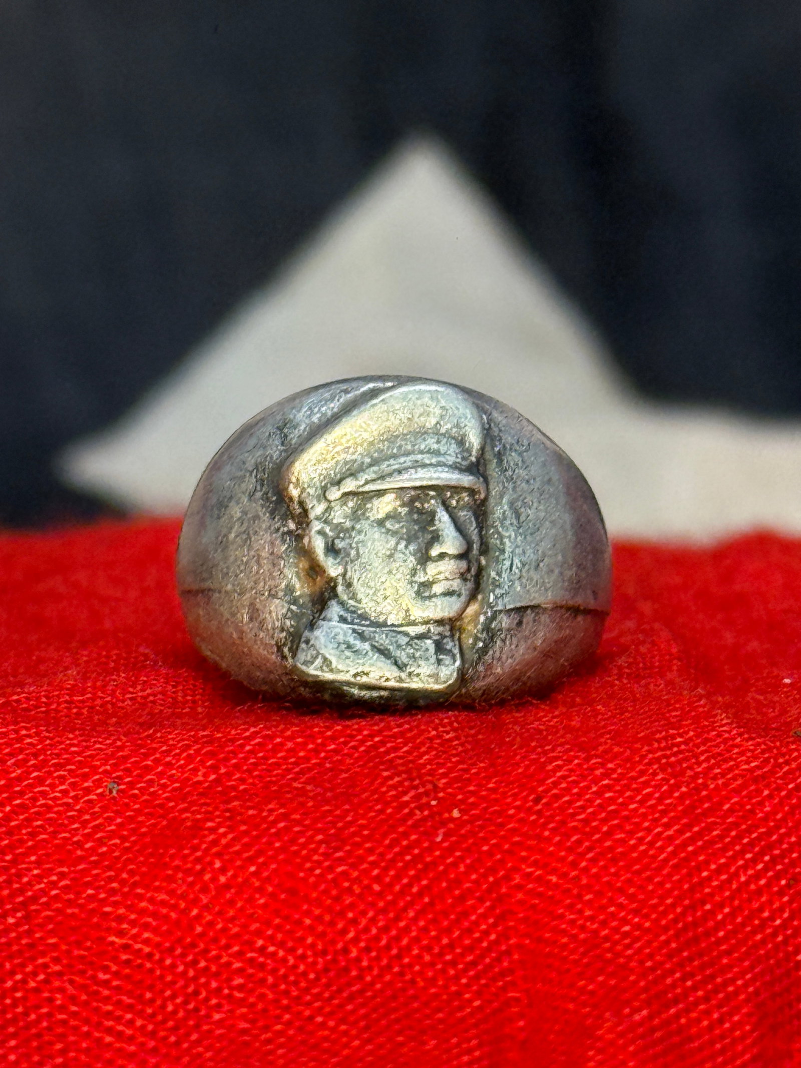 WWII German Benito Mussolini Portrait Ring: This metal ring features a raised portrait of Italian Fascist leader Benito Mussolini wearing his characteristic military cap. Rings of this nature were produced as patriotic or political jewelry duri