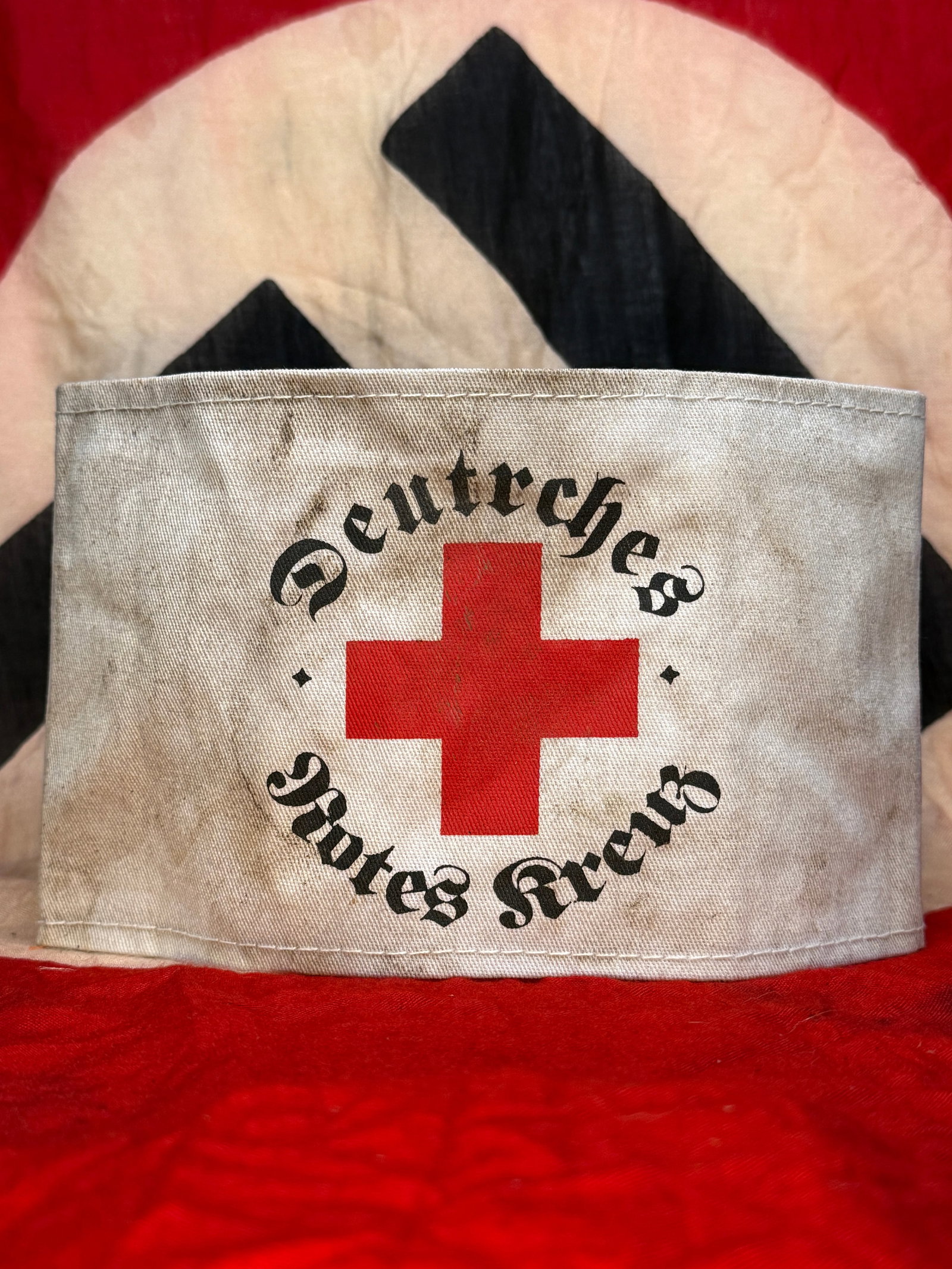 WWII German Deutsches Rotes Kreuz (German Red Cross) Armband: This white cloth armband displays a large red cross surrounded by the inscription "Deutsches Rotes Kreuz" in black Gothic lettering. Worn by members of the German Red Cross during the Second World War