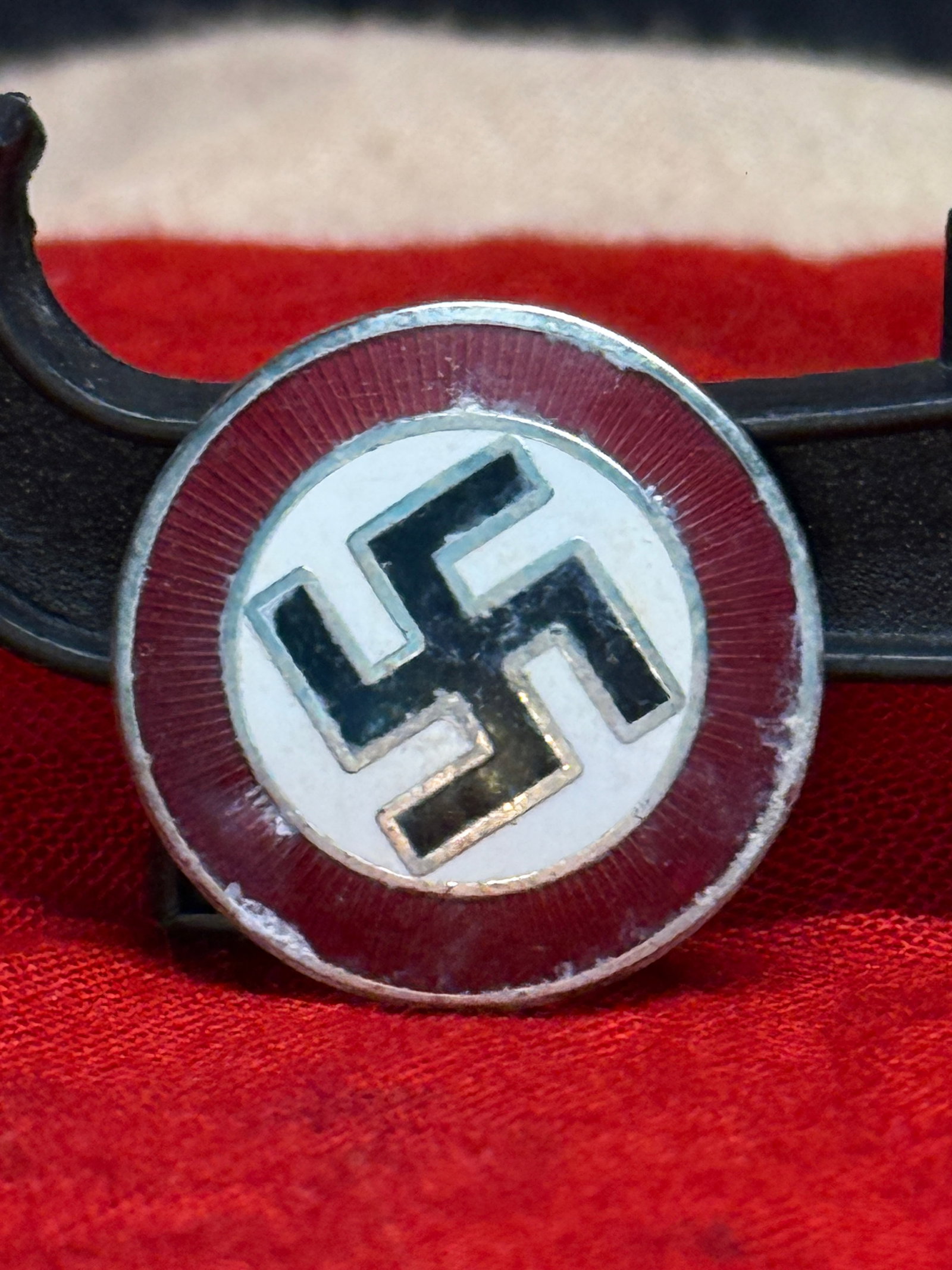 WWII German NSDAP Party Membership Enamel Pin Badge – RZM Marked: WWII German circular NSDAP-style membership pin featuring a black swastika centered on a white enamel field surrounded by a red enamel border. The reverse retains its horizontal pin and catch assembly