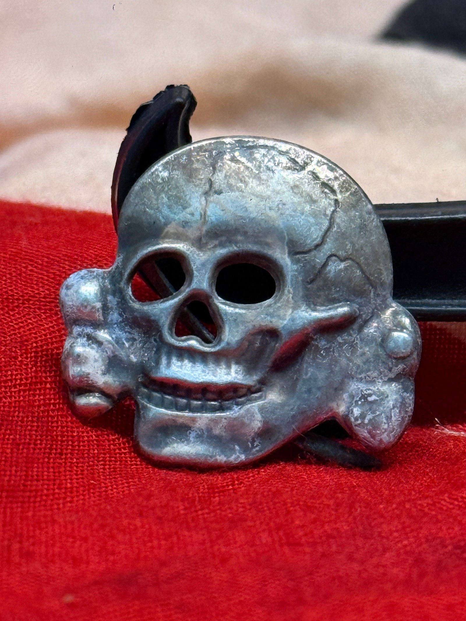 WWII German SS Totenkopf Cap Insignia: This stamped metal skull and crossbones insignia represents the famous SS Totenkopf emblem worn on various German SS visor caps and field caps during the Second World War. The skull exhibits detailed 