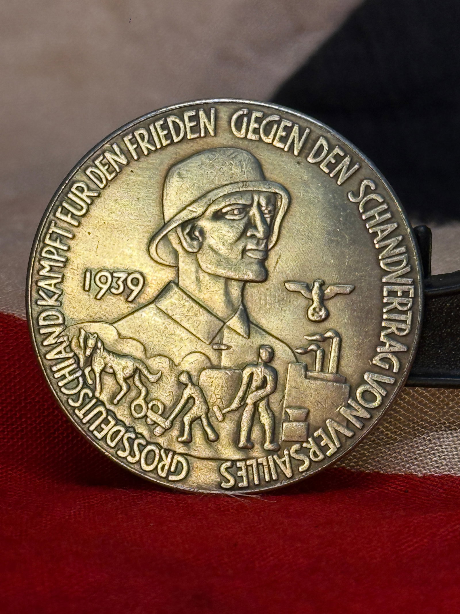 WWII German Anti-Bolshevik Propaganda Medal: This commemorative medal bears the inscription "Grossdeutschland kämpft für den Frieden gegen den Schandvertrag von Versailles" surrounding the bust of a German soldier dated 1939, with agricultural