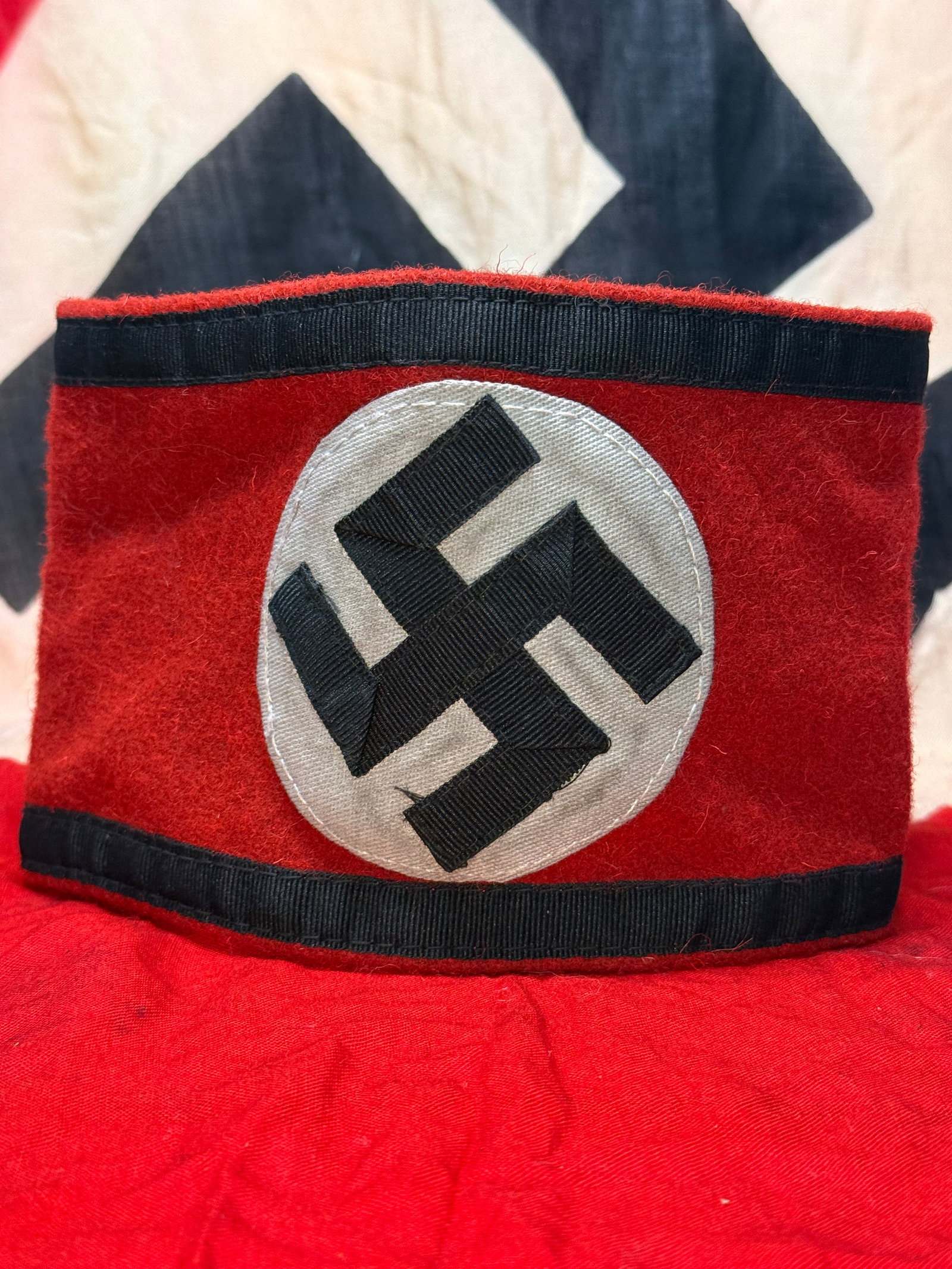 WWII German Allgemeine-SS Armband with RZM Tag: This red wool armband features a separately applied white roundel with a black ribbon swastika, trimmed with black borders and retaining its original RZM control label on the interior marked Herstelle