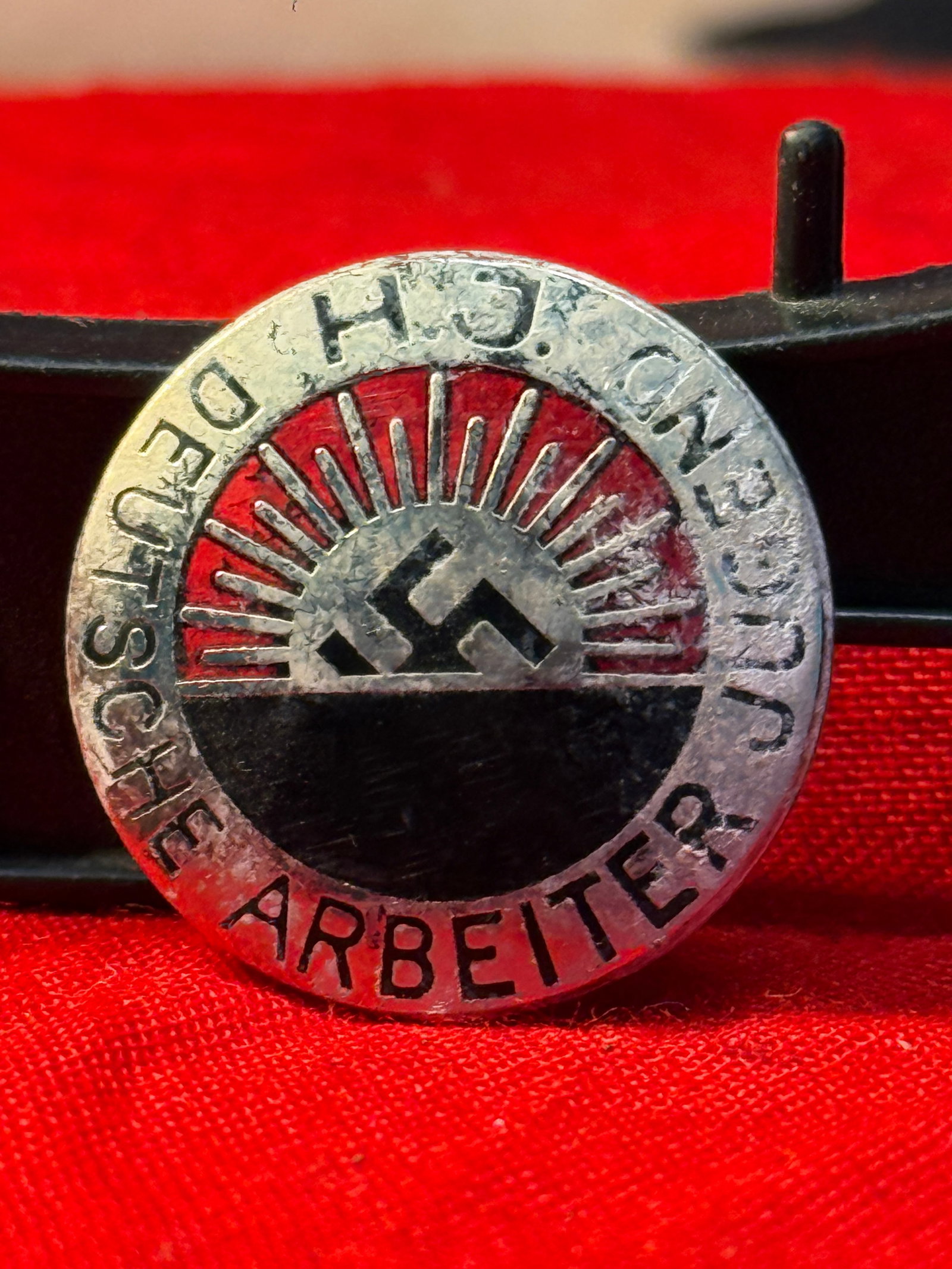 WWII German Hitler Youth DAJ Membership and Tradition Badge: This circular enameled badge displays the inscription "H.J. und D.A.J. Deutsche Arbeit" surrounding a rising sun with a central swastika motif. The reverse retains its original pin assembly and is mar