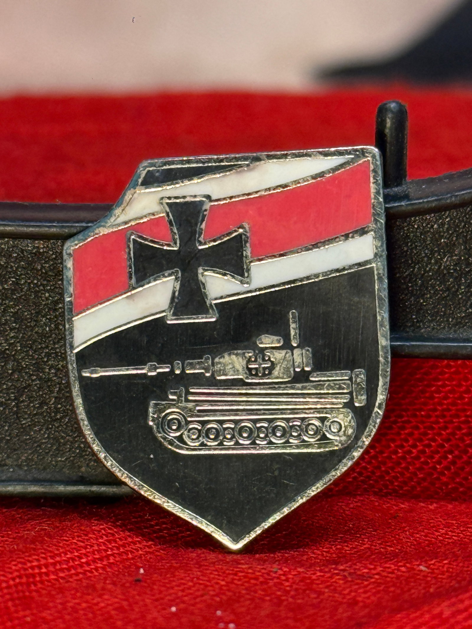 WWII German Panzer Division Commemorative Pin: This shield-shaped enameled pin depicts a German tank beneath an Iron Cross and the national colors, symbolizing the armored formations of the Wehrmacht during the Second World War. The detailed tank 