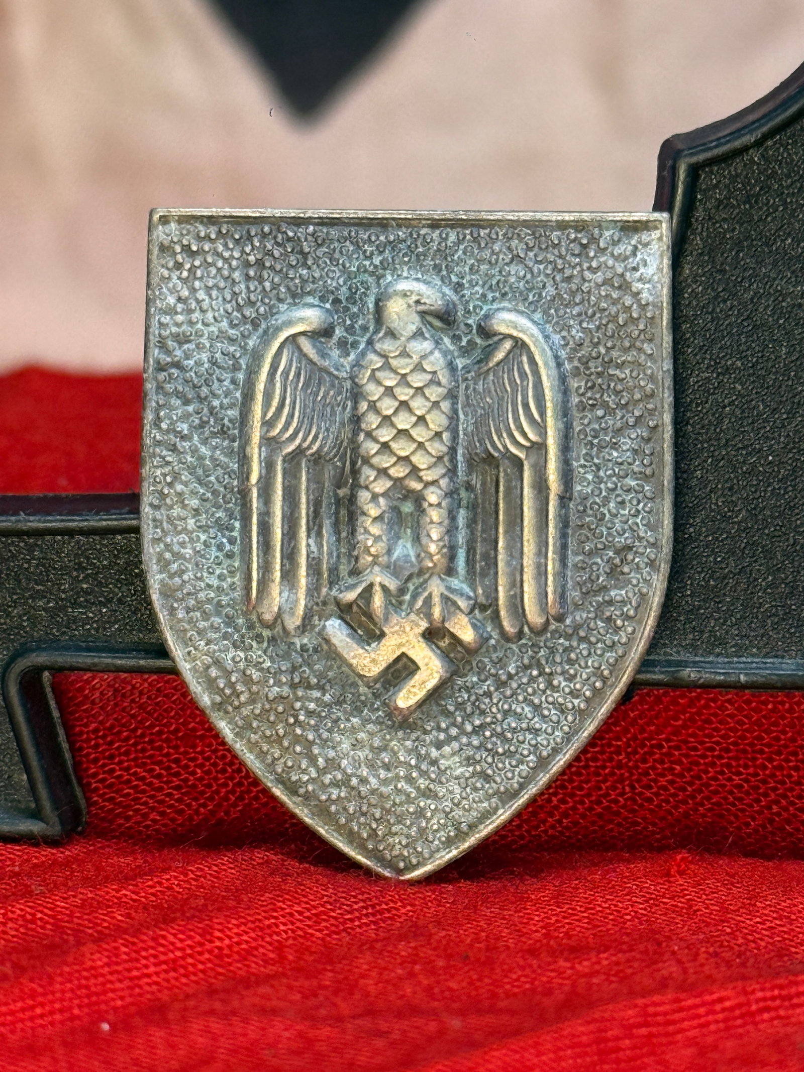 WWII German Army Marksmen's Eagle Lanyard Shield: This die-struck metal shield was designed for wear with the German Army Schützenschnur (Marksmen's Lanyard) and features the national eagle standing above a swastika on a textured shield. The reverse