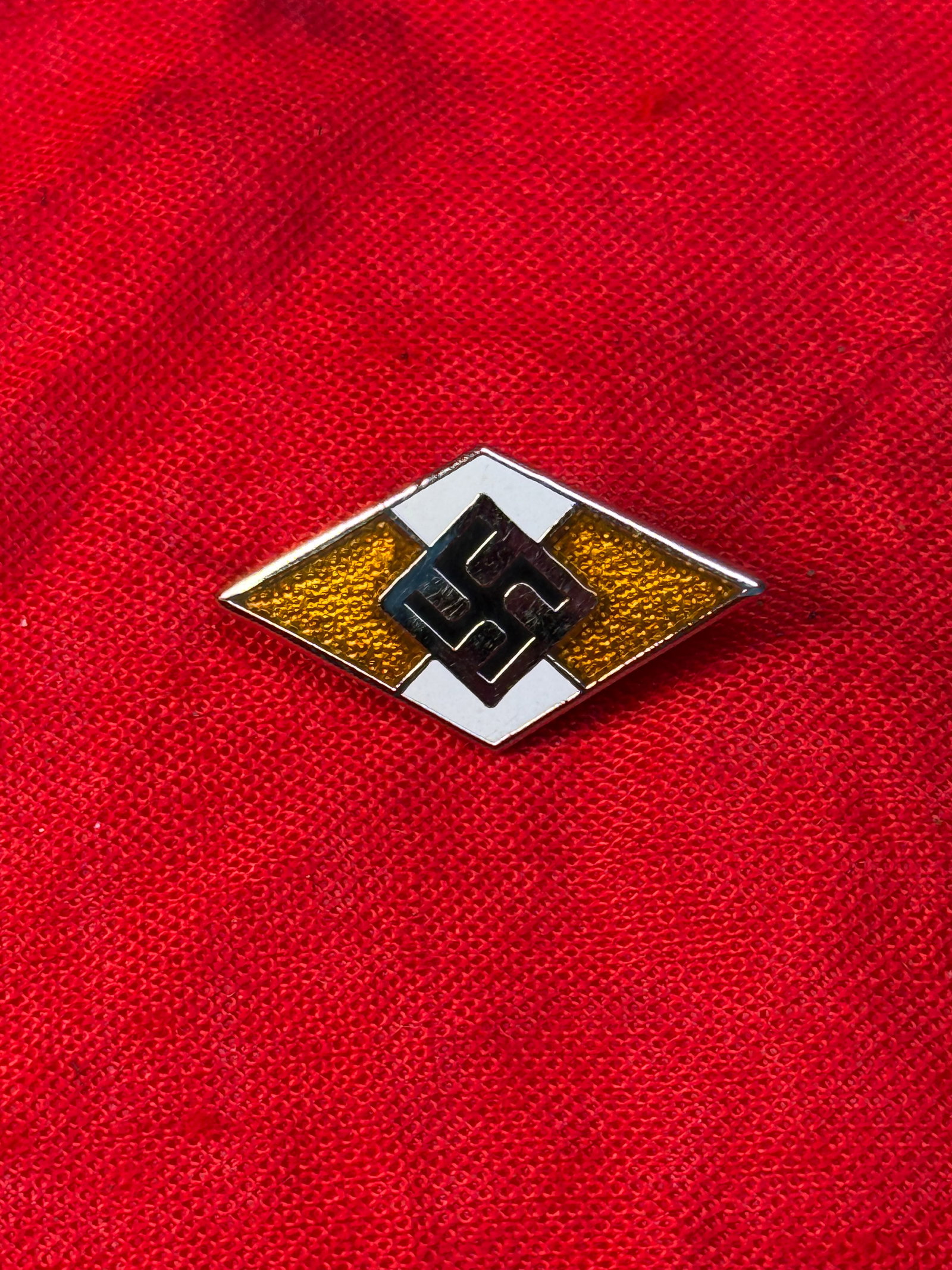 WWII German Hitler Youth HJ Membership Badge By Otto Hoffmann Ges. Gesch.: This diamond-shaped enameled badge features the distinctive Hitler Youth (Hitlerjugend) emblem with a black swastika centered within a white field bordered by red and white enamel. The reverse is make