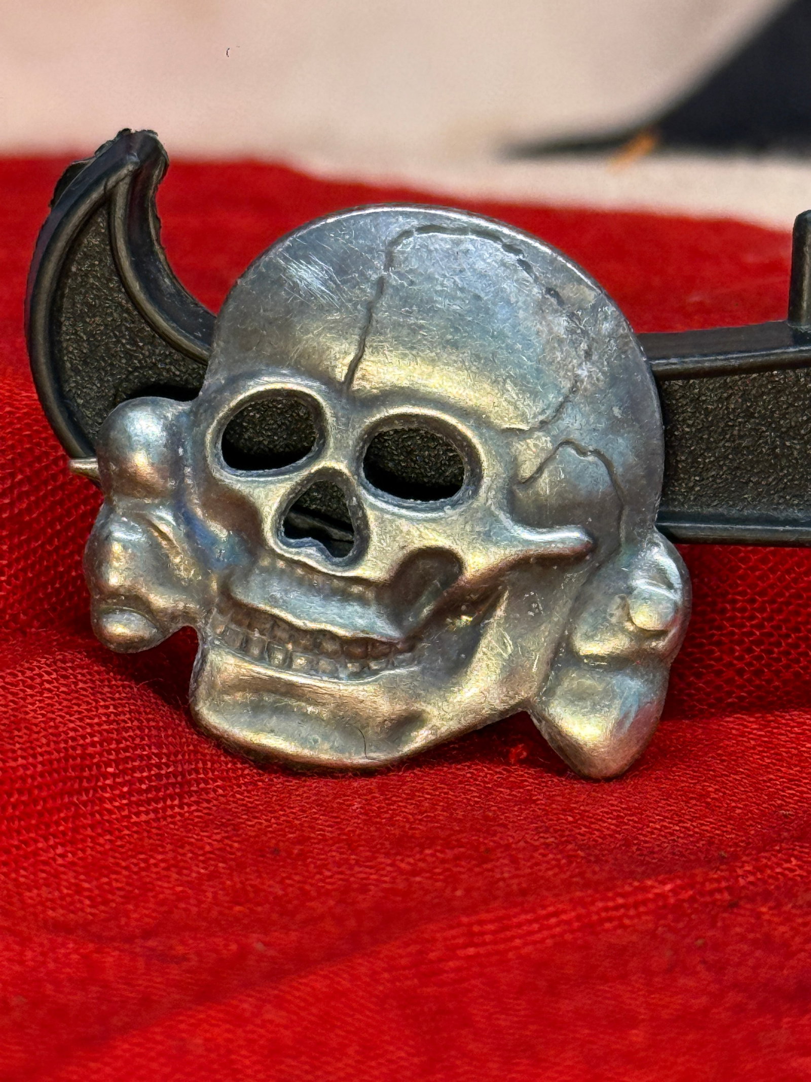 WWII German Waffen-SS Totenkopf Cap Insignia By RZM 254/4: This die-struck metal Totenkopf (Death's Head) cap insignia depicts the iconic skull and crossbones emblem associated with the Waffen-SS during the Second World War. The reverse retains its original a