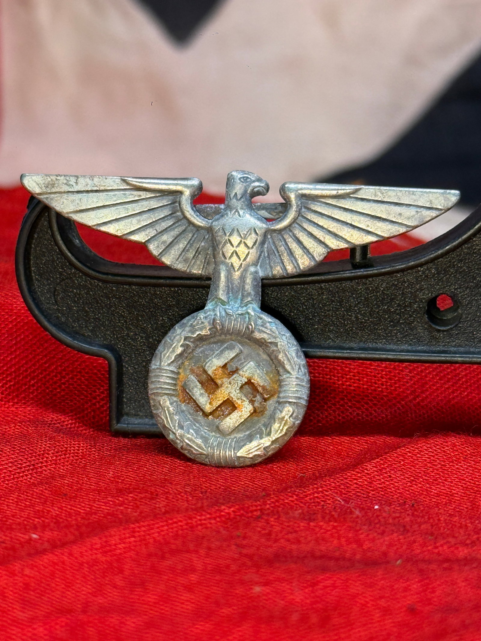 WWII German NSDAP Political Cap Eagle Insignia: This die-struck aluminum cap insignia features the distinctive spread-wing national eagle perched above a wreath enclosing a swastika, a design associated with the National Socialist German Workers' P
