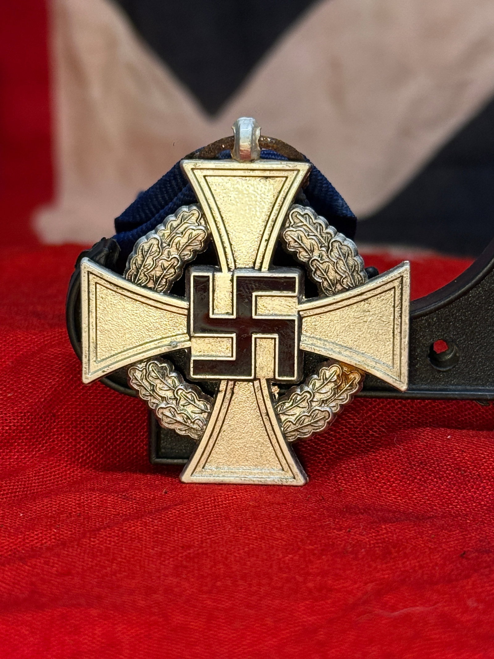 WWII German 25-Year Faithful Service Cross Medal: This suspended service decoration features a silvered cross superimposed over an oak leaf wreath with a black enameled swastika at its center. The reverse bears the inscription "Für treue Dienste" ("