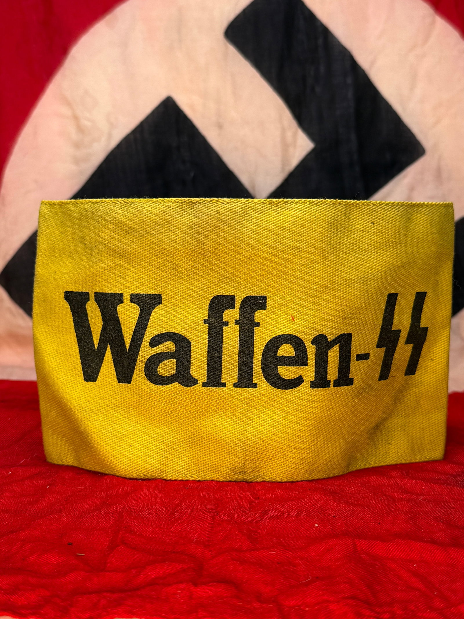 WWII German Waffen-SS Yellow Armband with RZM Tag: This yellow cloth armband is boldly printed "Waffen-SS" across the front and retains its original interior RZM (Reichszeugmeisterei) paper control label with SS acceptance markings and manufacturer in