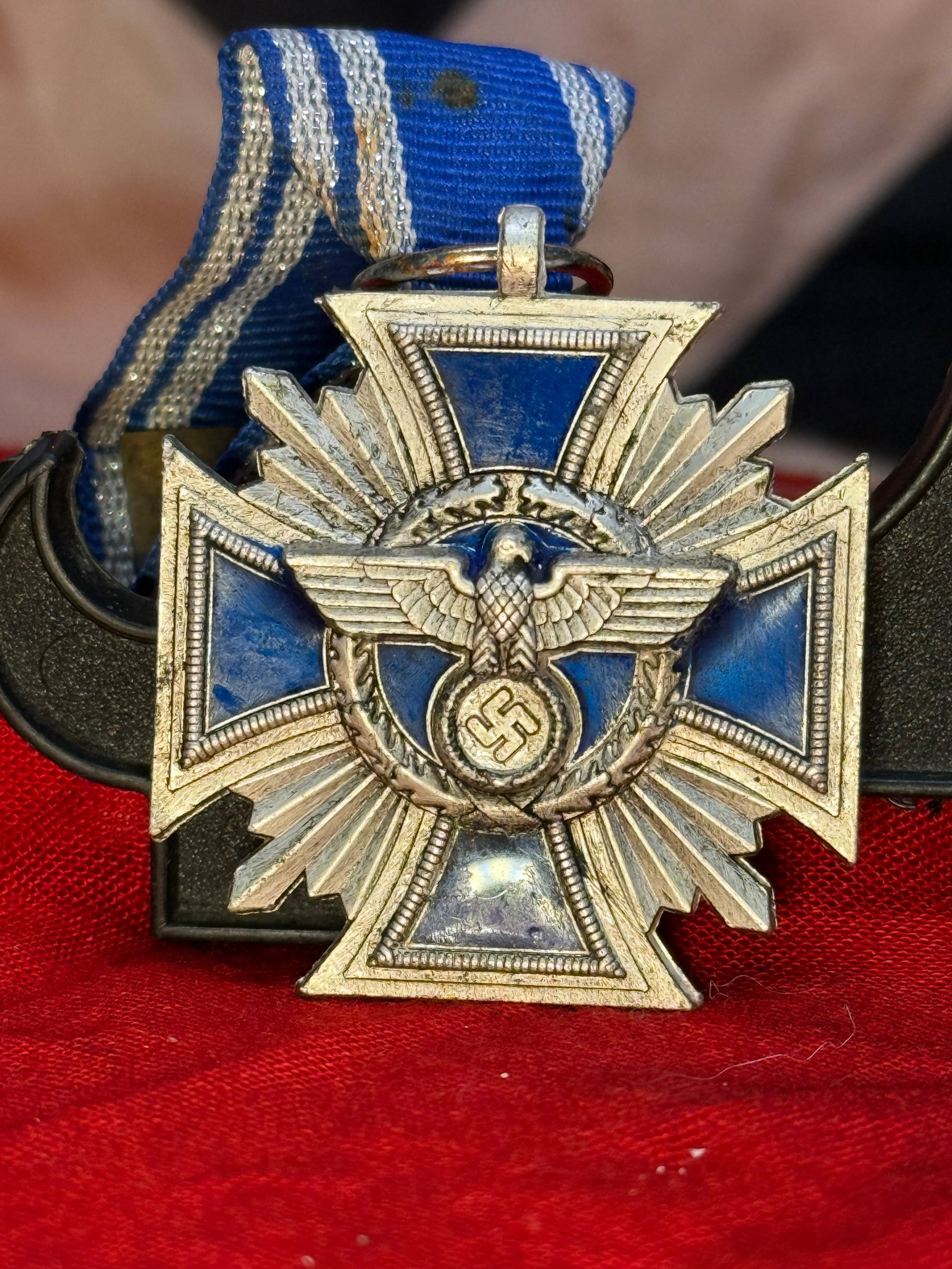 WWII German 25-Year Faithful Service Decoration: This silvered Maltese cross features blue enameled arms with the national eagle and swastika on one side and the inscription "Treue für Führer und Volk" ("Loyalty for Leader and People") on the reve