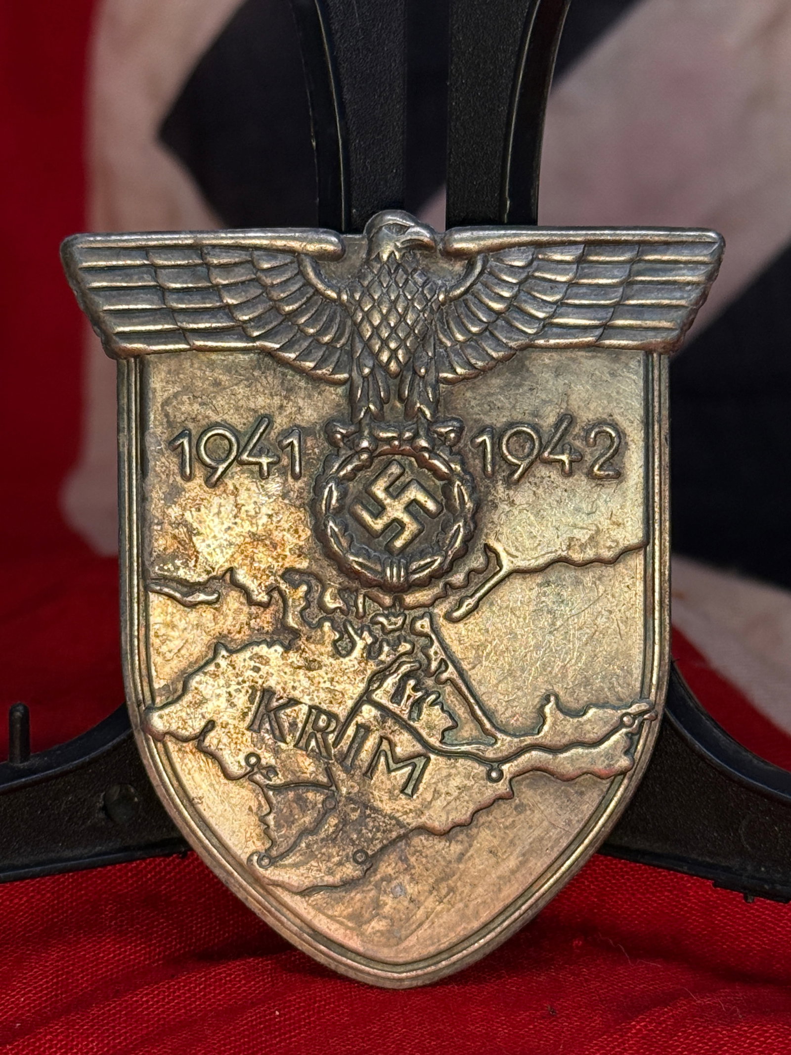 WWII German Crimea Campaign Shield (Krimschild): This shield-shaped campaign award features the German national eagle above the dates 1941–1942, a wreath enclosing a swastika, and a detailed relief map of the Crimean Peninsula bearing the inscript