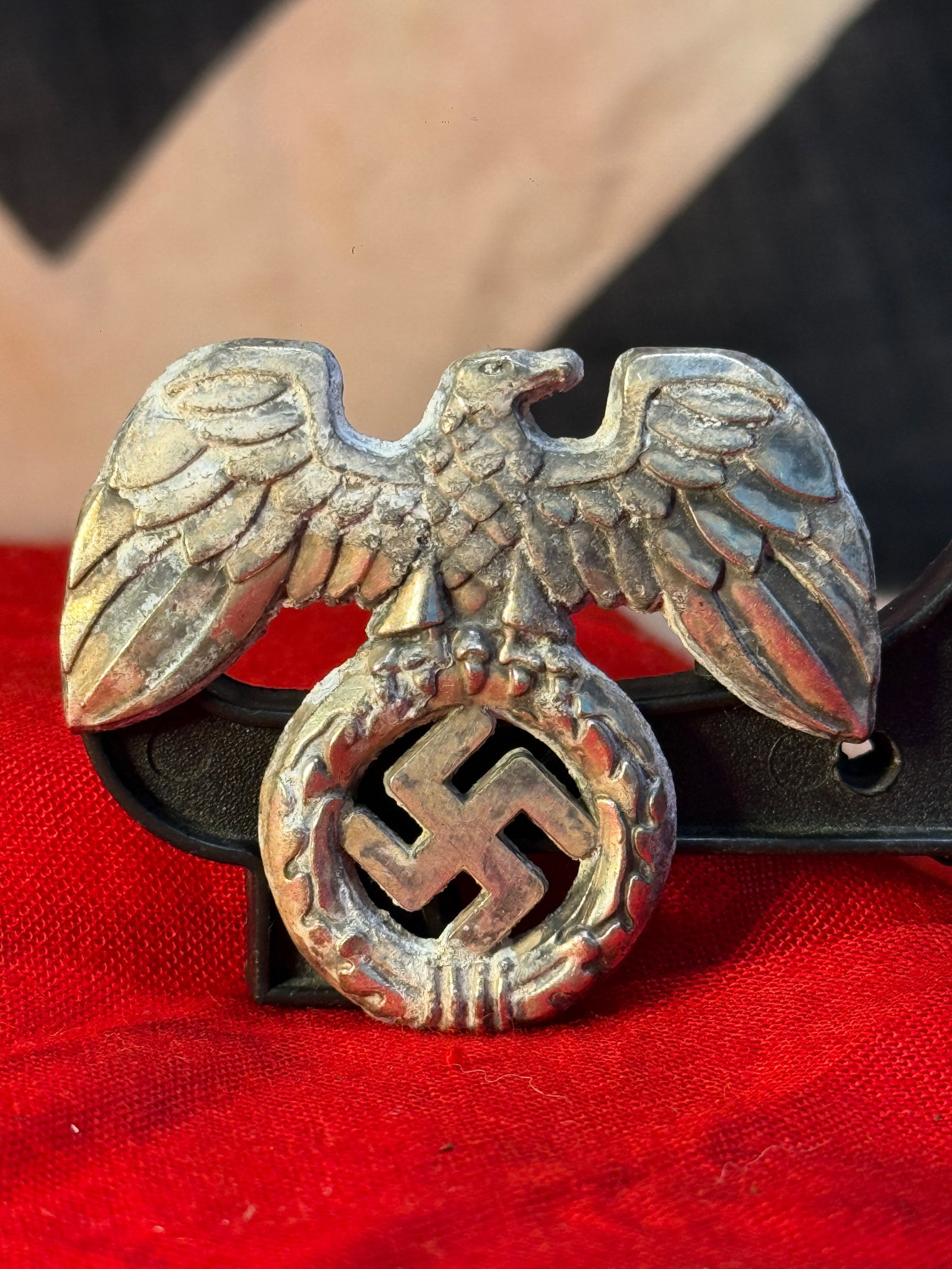 WWII German Political Eagle Cap Insignia: This WWII German political eagle cap insignia depicts the national eagle with outstretched wings clutching a wreath containing a swastika. Constructed of die-struck metal, this style of insignia was w